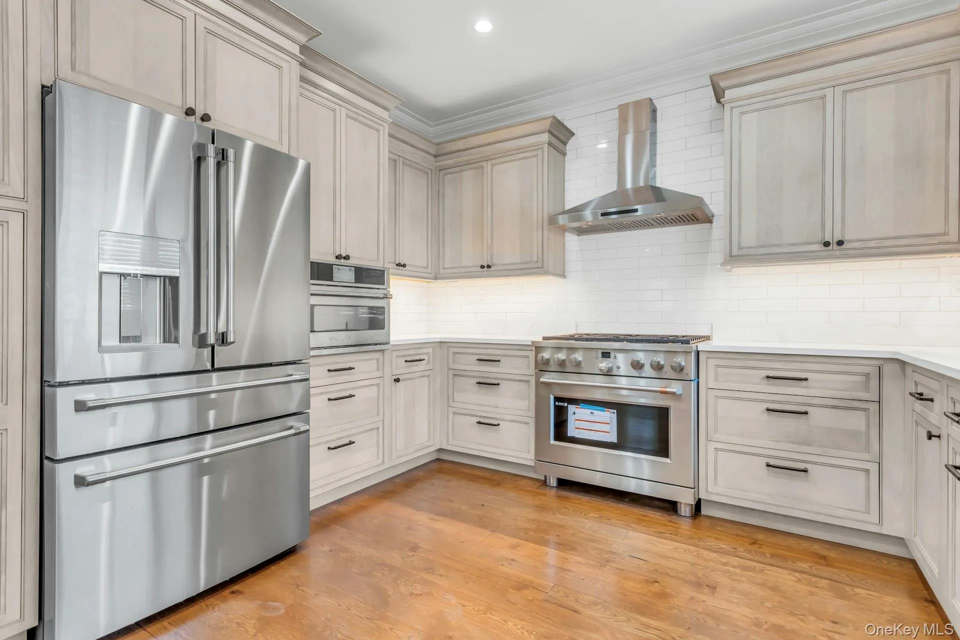 The kitchen features stainless steel appliances, including a refrigerator, wall oven, and range with a hood The kitchen features stainless steel appliances, including a refrigerator, wall oven, and range with a hood
