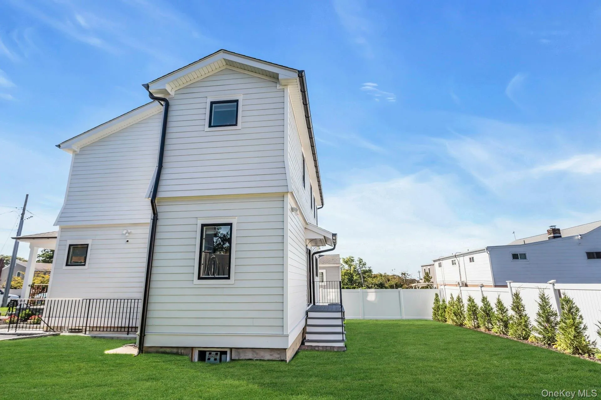 The property features white siding, dark-framed windows, and a well-maintained green lawn The property features white siding, dark-framed windows, and a well-maintained green lawn