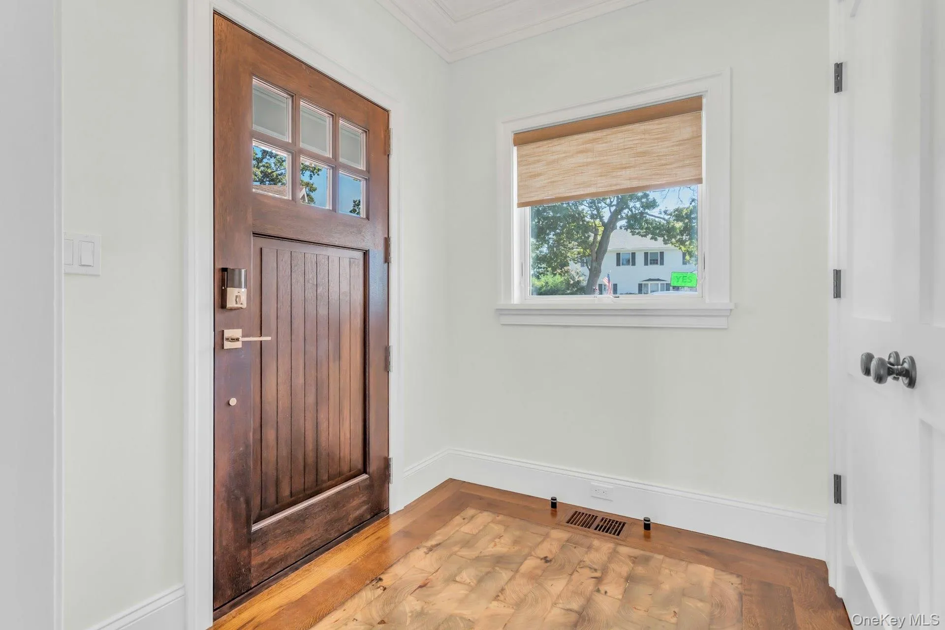 Entryway featuring a rich wood paneled door with glass inserts, a window with a natural shade, and hardwood flooring Entryway featuring a rich wood paneled door with glass inserts, a window with a natural shade, and hardwood flooring