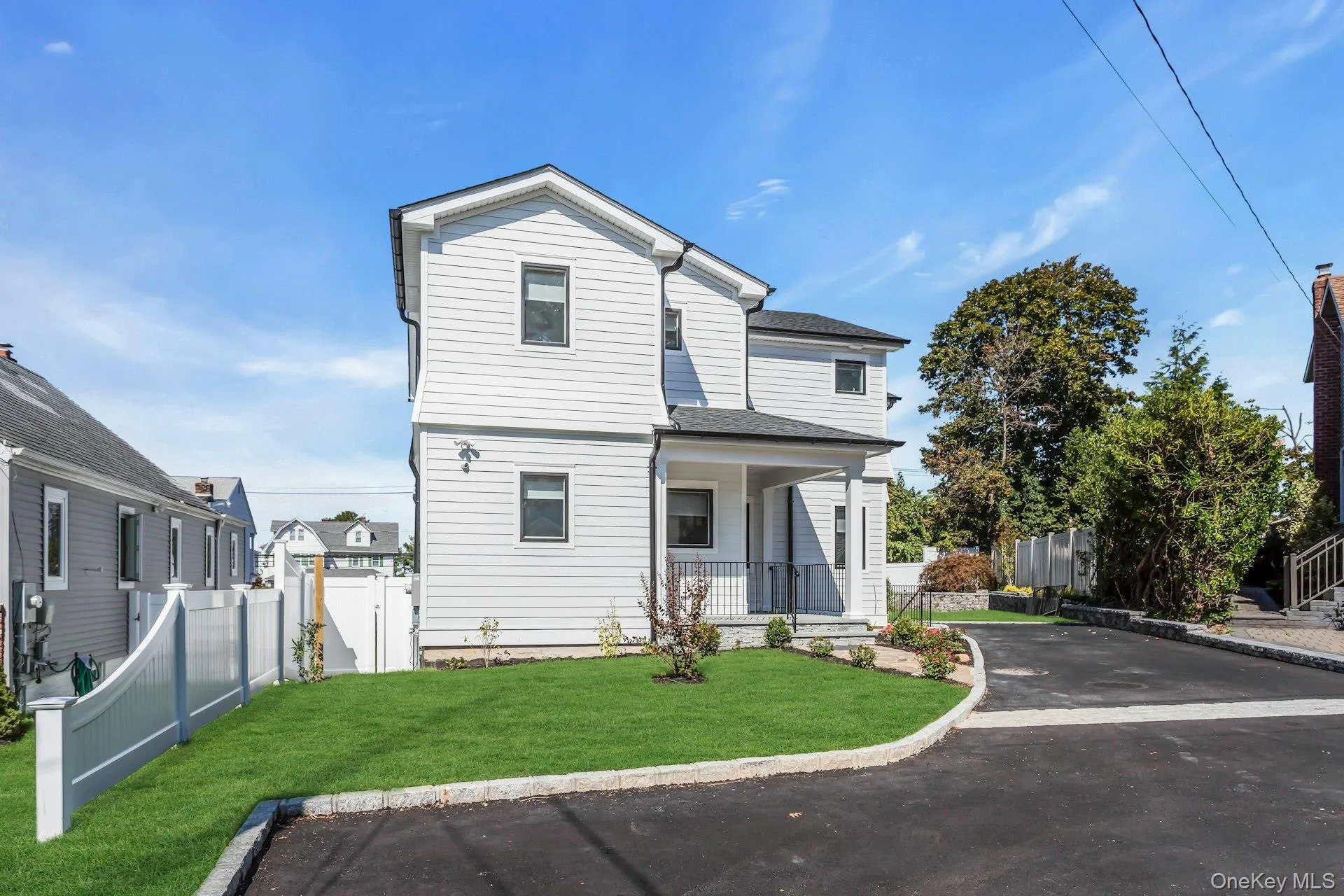 The property features a well-maintained lawn, a paved driveway, and a white fence The property features a well-maintained lawn, a paved driveway, and a white fence