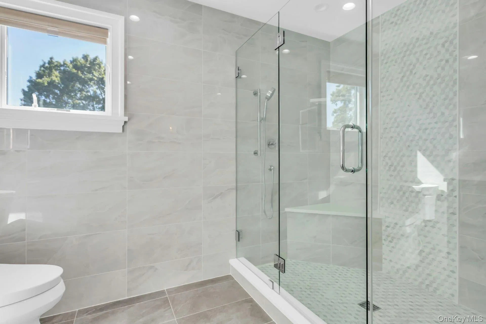 Contemporary bathroom with light-toned wall tiles, a glass-enclosed shower with multiple shower heads, and an integrated shower bench Contemporary bathroom with light-toned wall tiles, a glass-enclosed shower with multiple shower heads, and an integrated shower bench