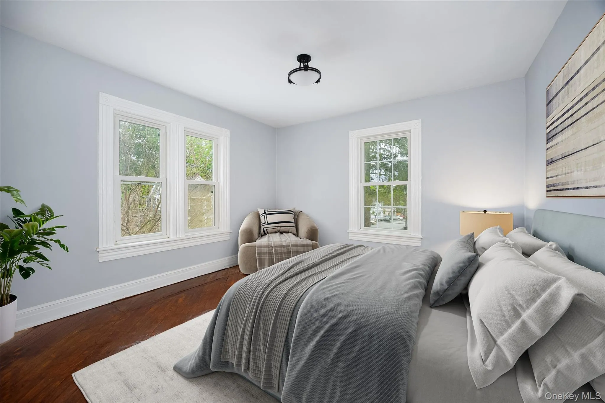 Bedroom featuring light gray walls, hardwood flooring, white baseboards, and white window trim. Bedroom featuring light gray walls, hardwood flooring, white baseboards, and white window trim.