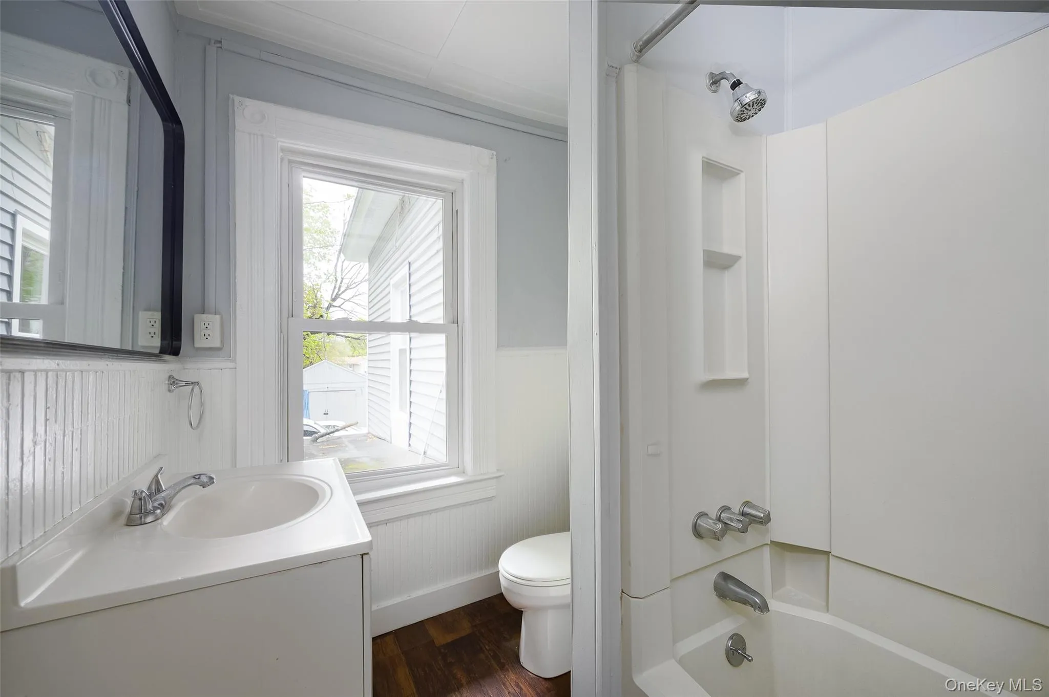 Bathroom featuring a single vanity with an integrated sink, chrome faucet, and a wall-mounted mirror Bathroom featuring a single vanity with an integrated sink, chrome faucet, and a wall-mounted mirror