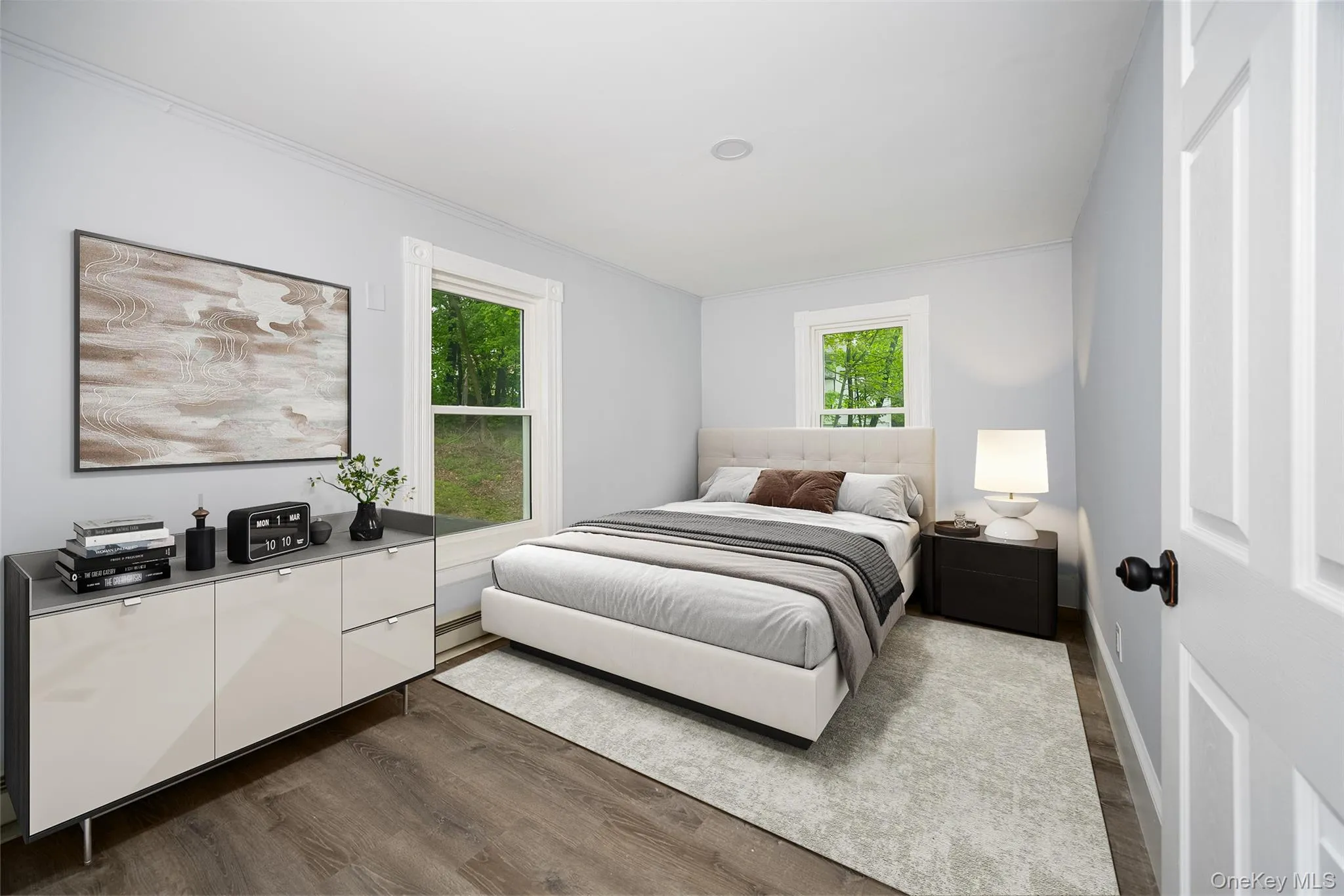 Interior room featuring wood-finish flooring, light gray walls, white trim, and two windows. Interior room featuring wood-finish flooring, light gray walls, white trim, and two windows.