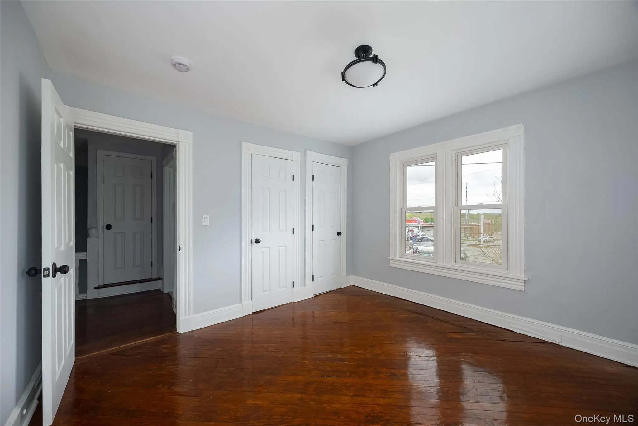 Room featuring rich wood flooring, light grey wall paint, and white trim Room featuring rich wood flooring, light grey wall paint, and white trim