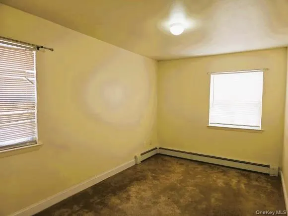 Bedroom 1 features neutral-toned walls, two windows with blinds, a ceiling-mounted light fixture, and carpeted flooring Bedroom 1 features neutral-toned walls, two windows with blinds, a ceiling-mounted light fixture, and carpeted flooring