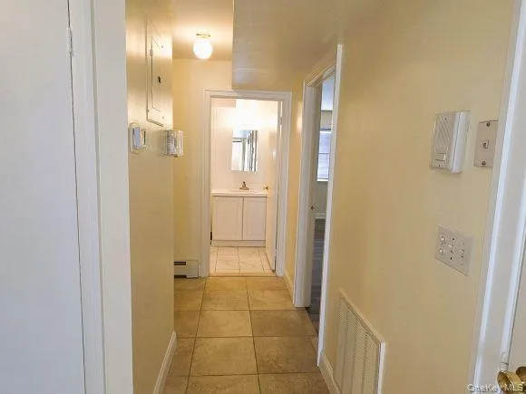 Hallway to bed and bath features light-colored walls and tiled flooring Hallway to bed and bath features light-colored walls and tiled flooring