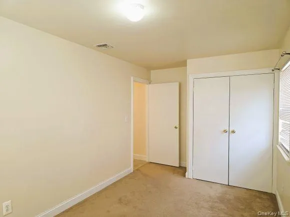 Bedroom 1 features neutral colored carpeting, light-toned walls, and a ceiling-mounted light fixture Bedroom 1 features neutral colored carpeting, light-toned walls, and a ceiling-mounted light fixture
