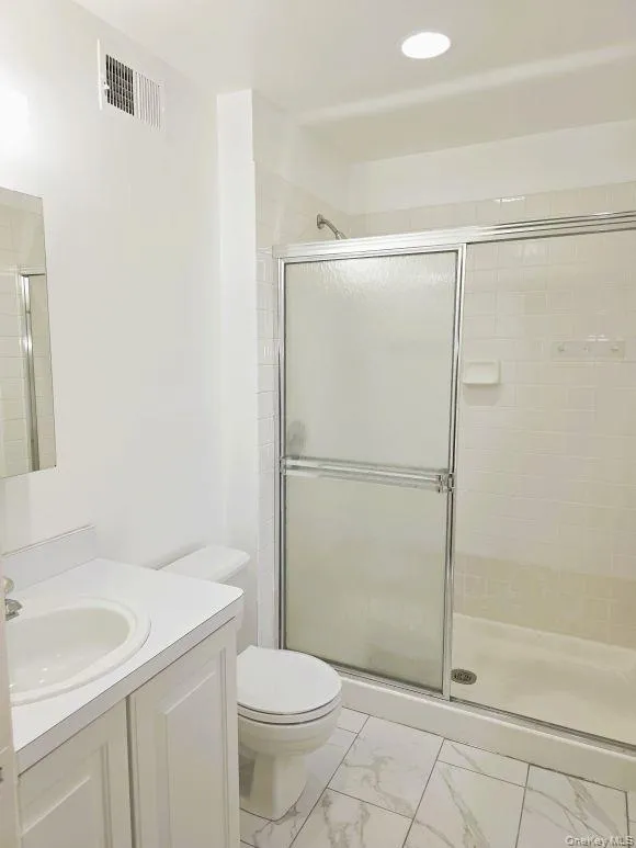 Master bathroom featuring a vanity with an integrated sink, a toilet, a shower with sliding glass doors, and tiled flooring Master bathroom featuring a vanity with an integrated sink, a toilet, a shower with sliding glass doors, and tiled flooring