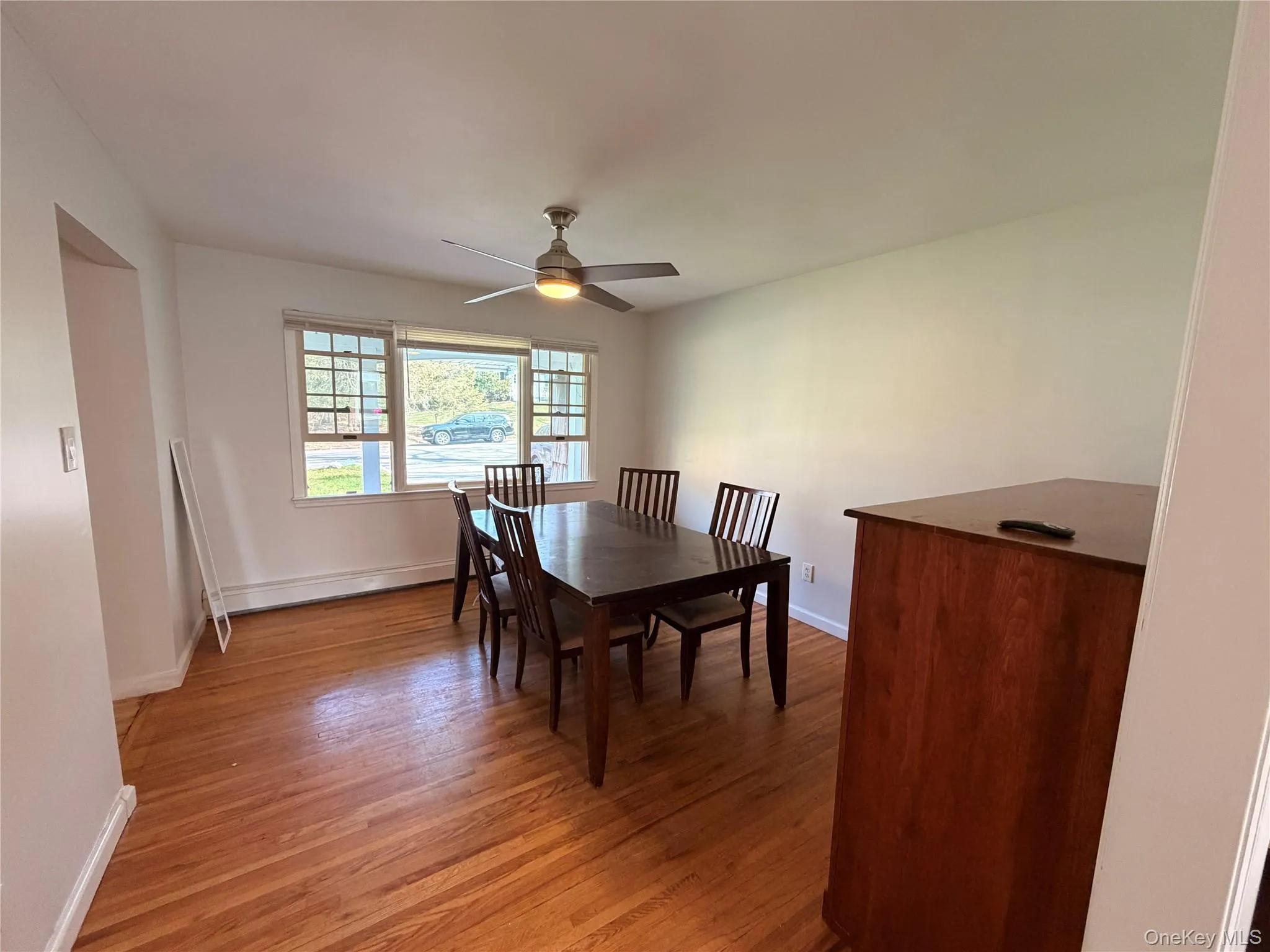 This interior space features wood flooring, white walls, and a ceiling fan This interior space features wood flooring, white walls, and a ceiling fan