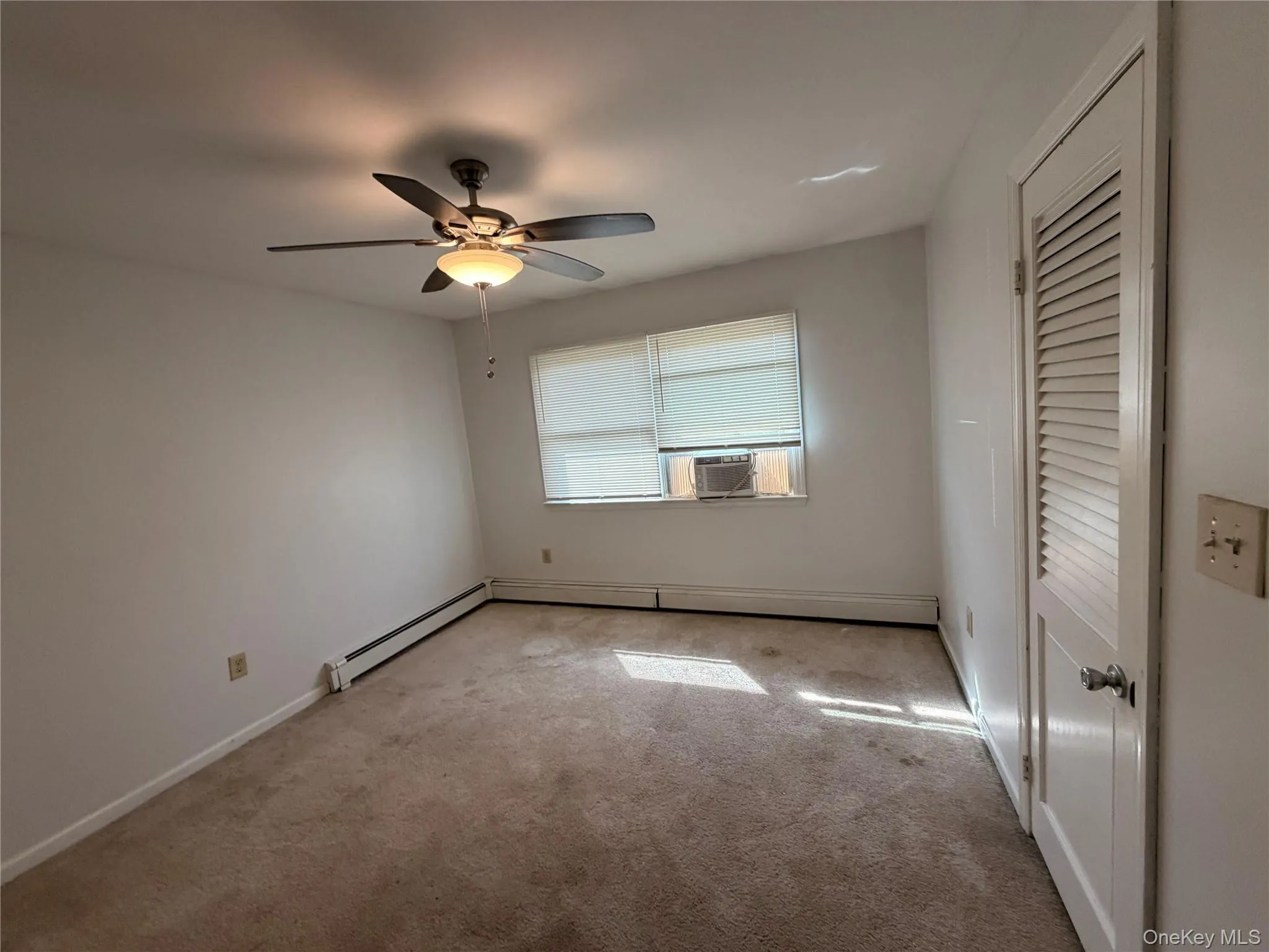 This room features light-colored walls, carpeted flooring, and a ceiling fan with an integrated light fixture This room features light-colored walls, carpeted flooring, and a ceiling fan with an integrated light fixture