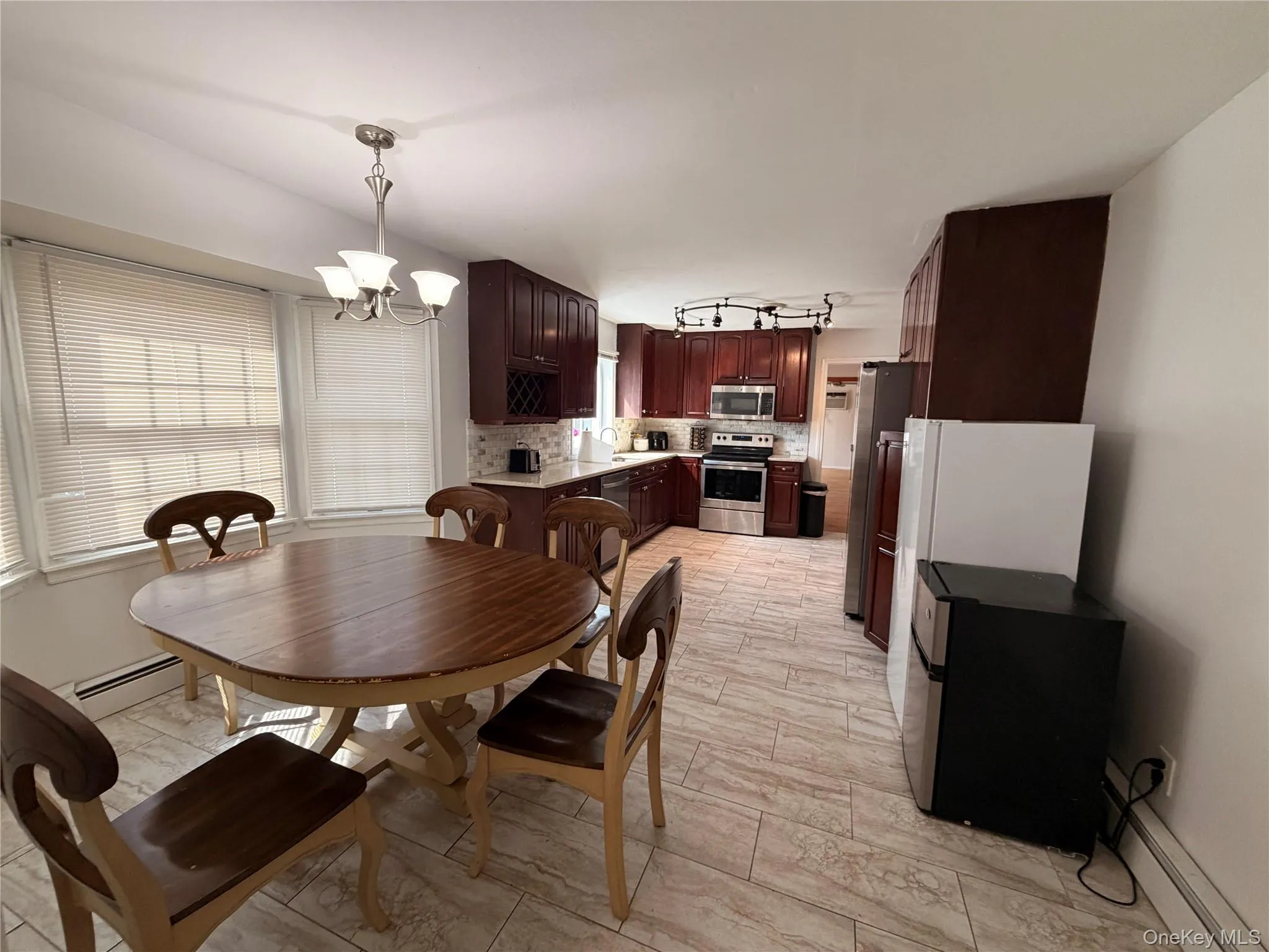 The kitchen features dark wood cabinetry, stainless steel appliances, and a tiled backsplash The kitchen features dark wood cabinetry, stainless steel appliances, and a tiled backsplash