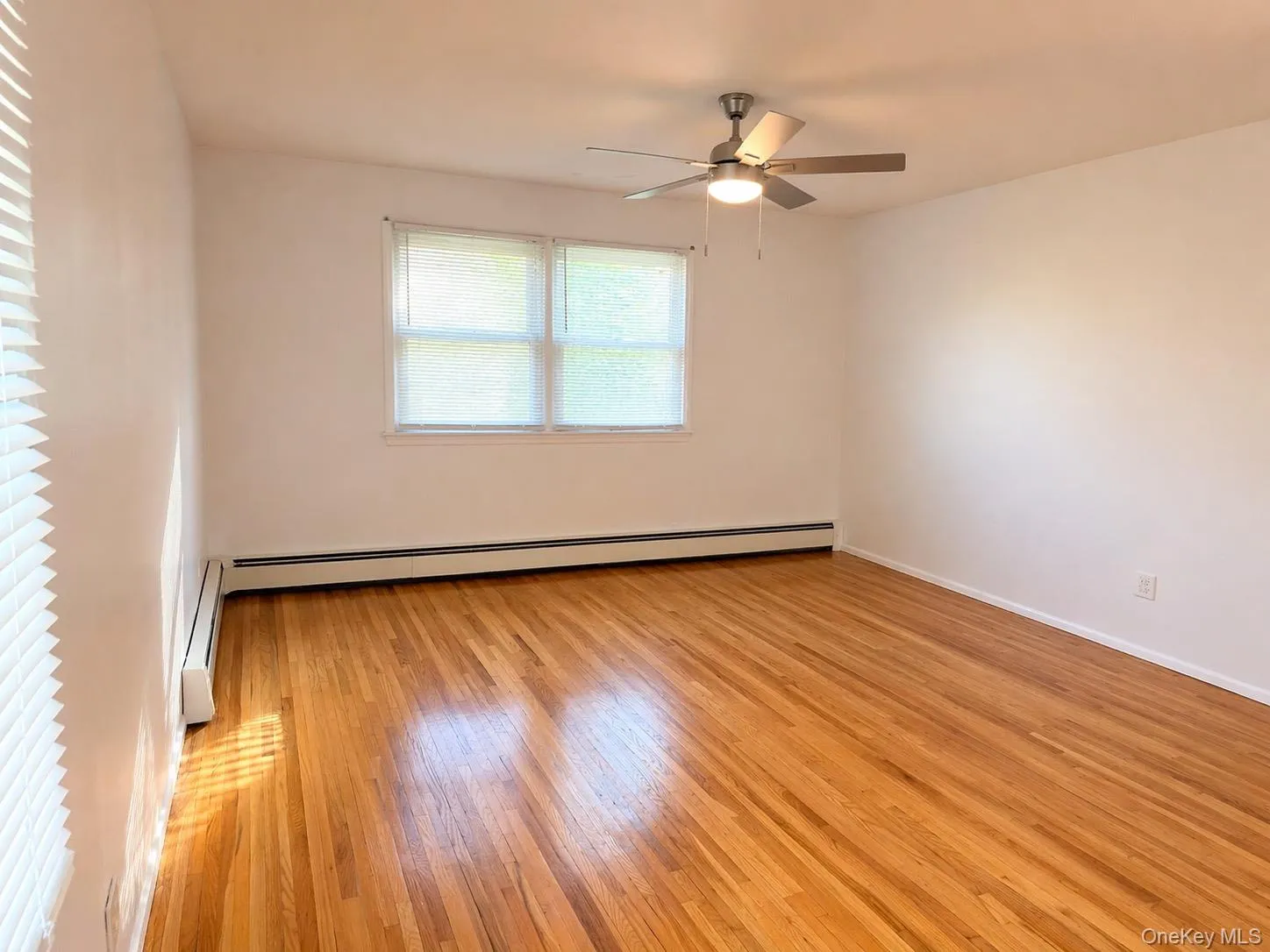 This room features hardwood floors, white walls, and a ceiling fan with integrated lighting This room features hardwood floors, white walls, and a ceiling fan with integrated lighting