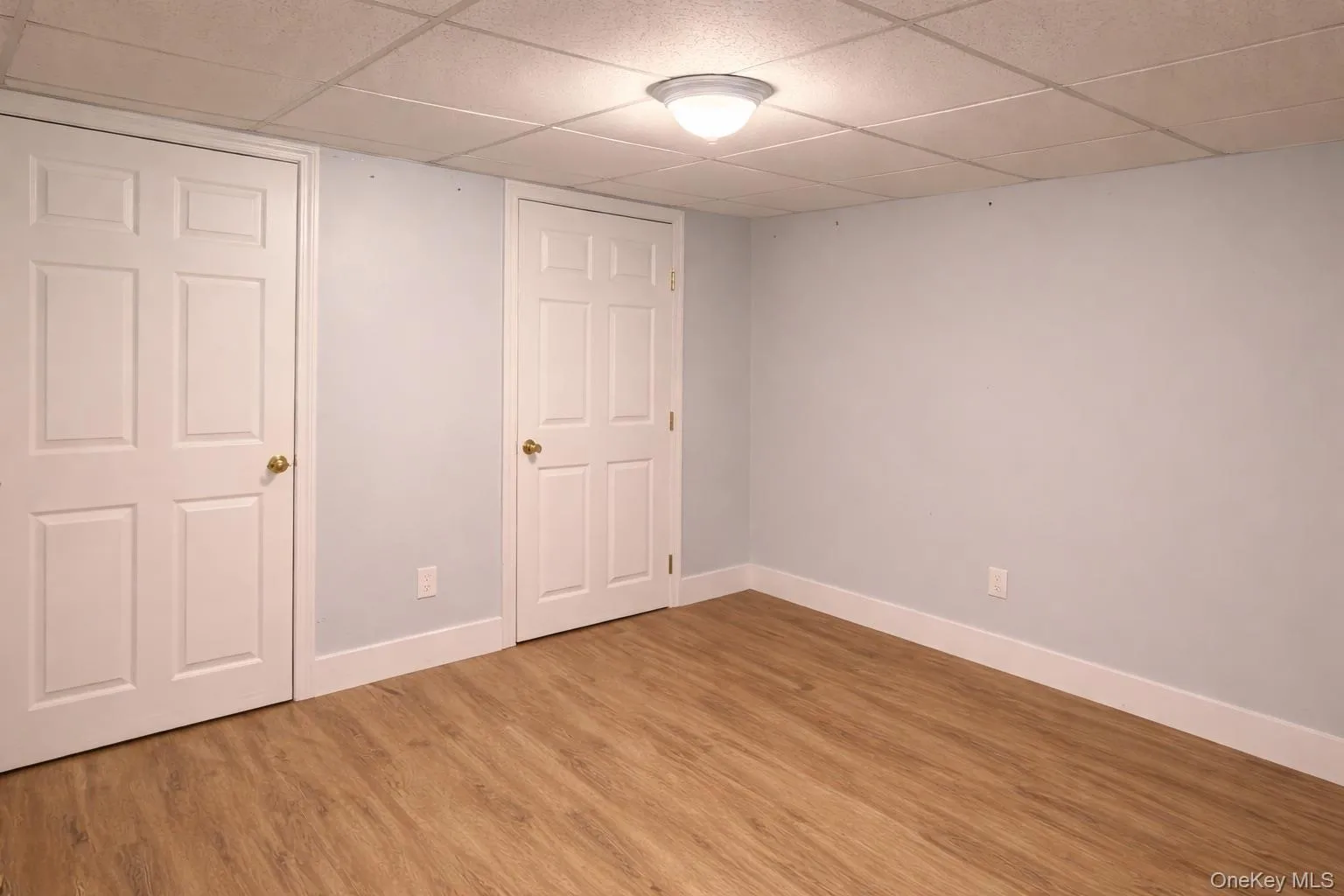 This room features light wood-look flooring, light blue walls, and a white drop ceiling with recessed lighting This room features light wood-look flooring, light blue walls, and a white drop ceiling with recessed lighting