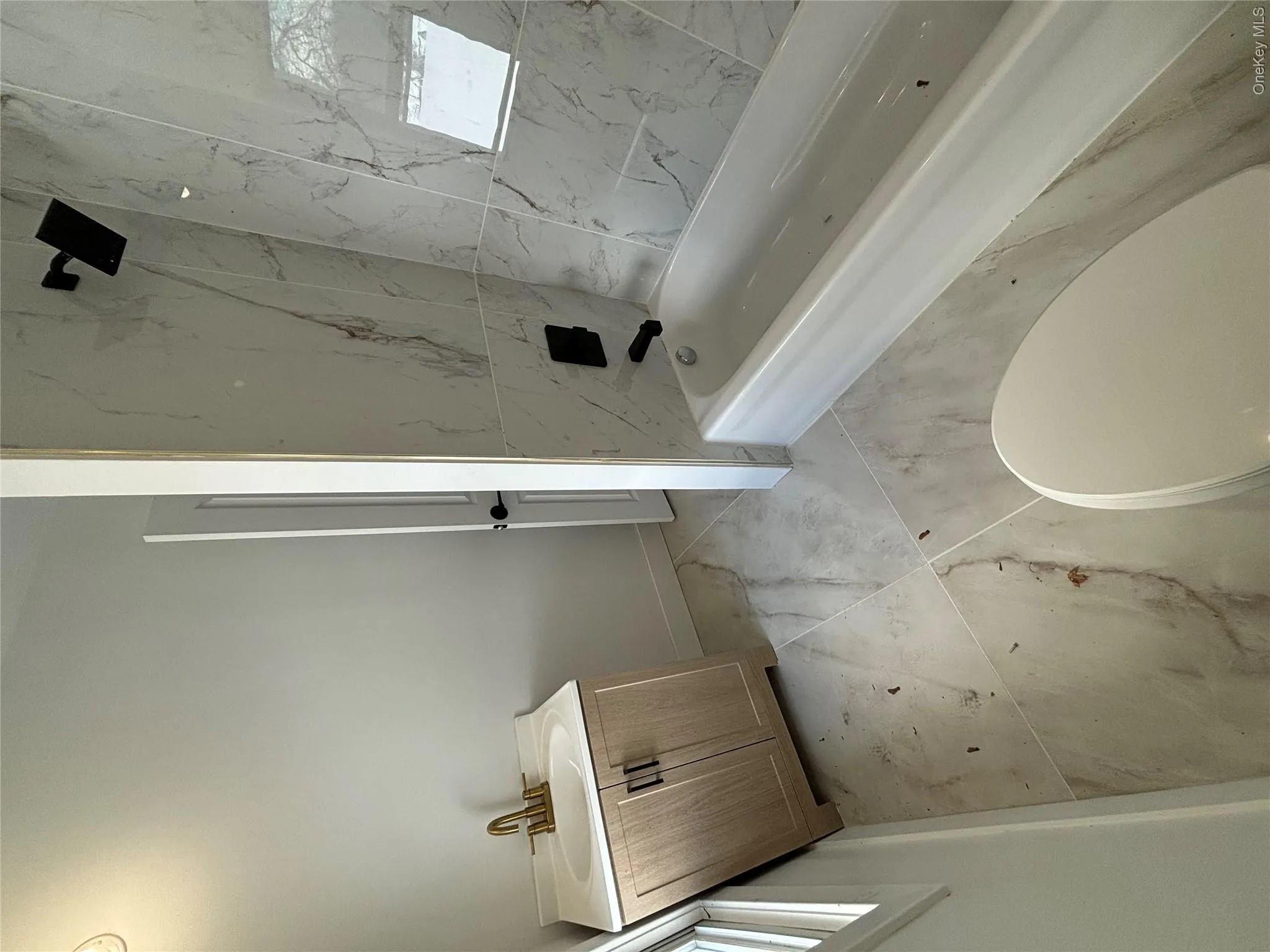 Bathroom with vanity, shower / tub combination, and light marble finish floors Bathroom with vanity, shower / tub combination, and light marble finish floors