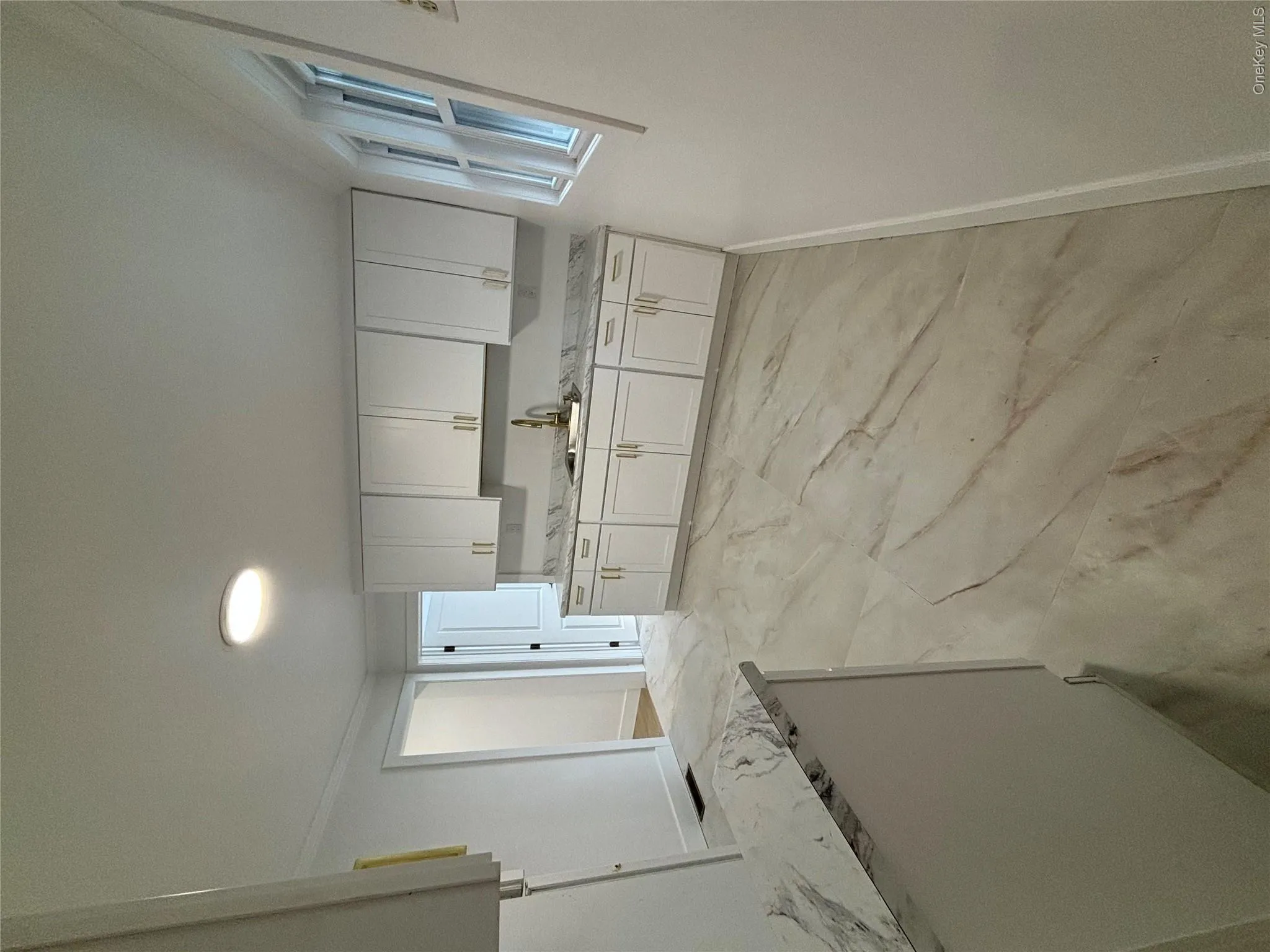 Kitchen with white cabinets, light stone countertops, and ornamental molding Kitchen with white cabinets, light stone countertops, and ornamental molding