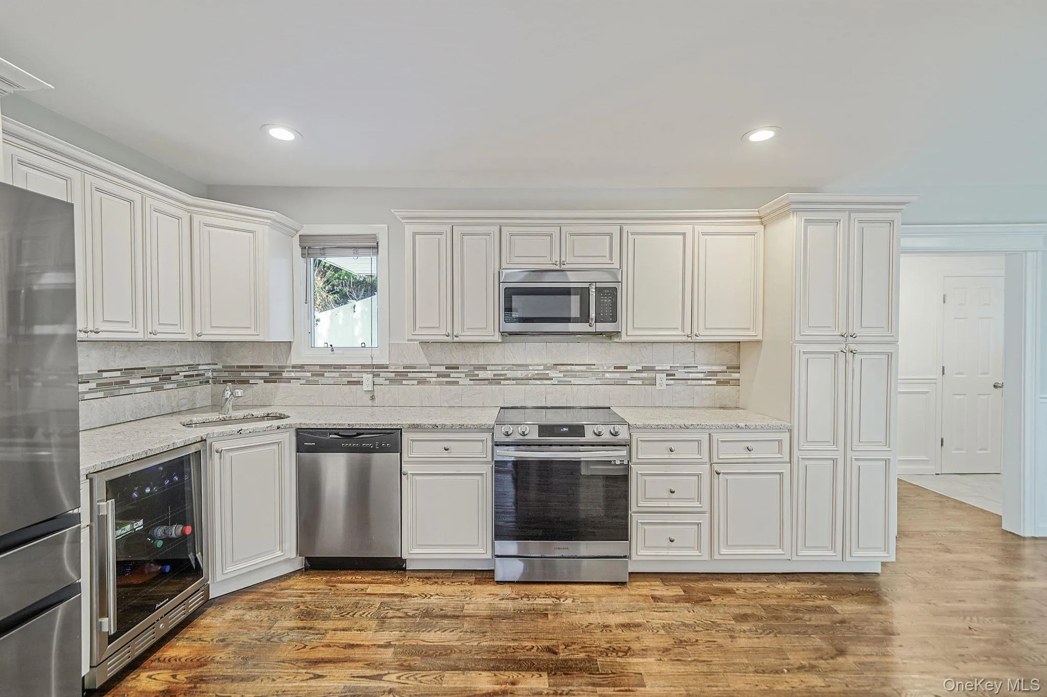 The kitchen features white cabinetry, stainless steel appliances, speckled countertops, and a patterned backsplash The kitchen features white cabinetry, stainless steel appliances, speckled countertops, and a patterned backsplash
