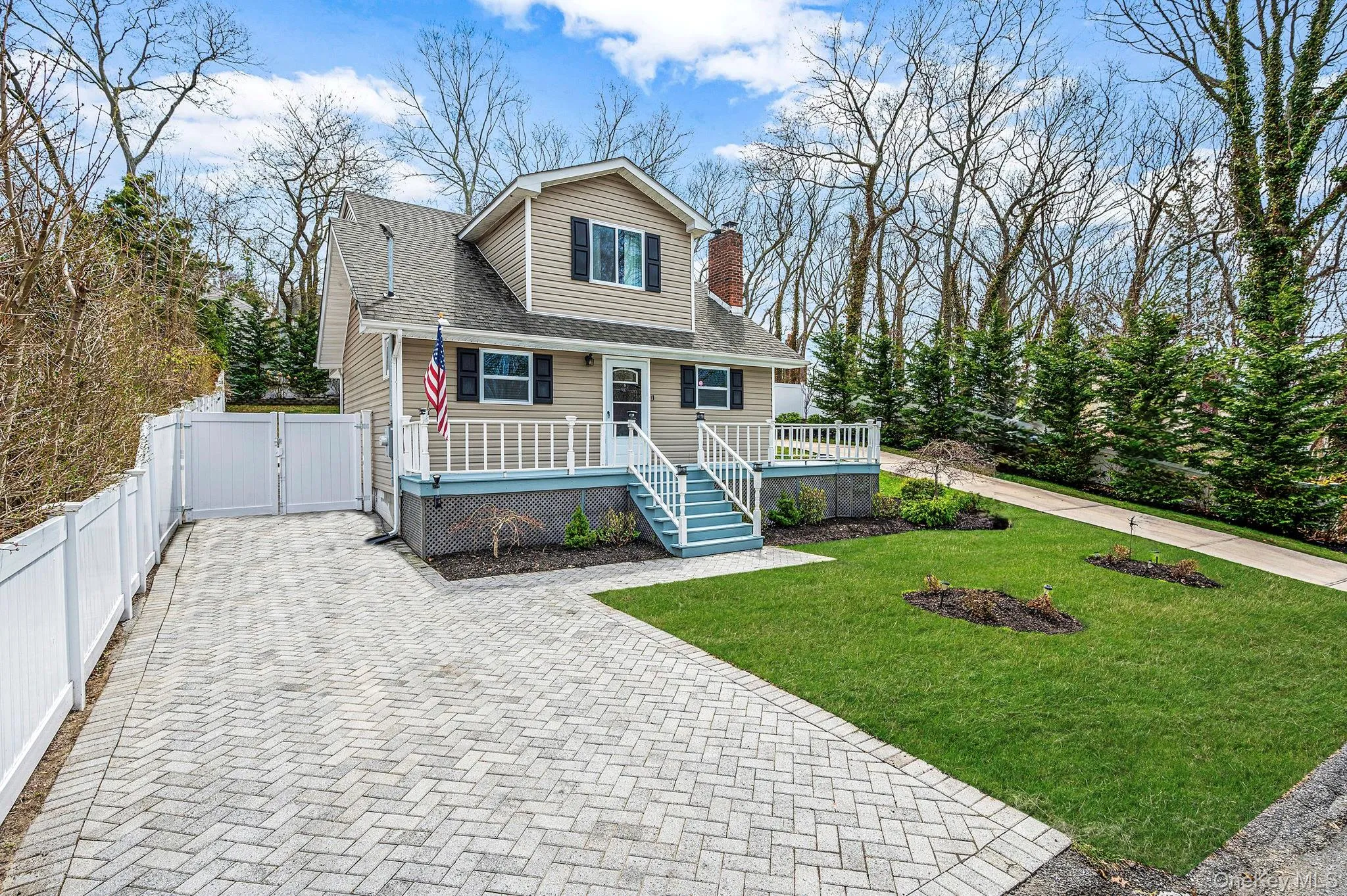 The property features a well-maintained lawn, a paved driveway, and a welcoming front porch with white railings The property features a well-maintained lawn, a paved driveway, and a welcoming front porch with white railings