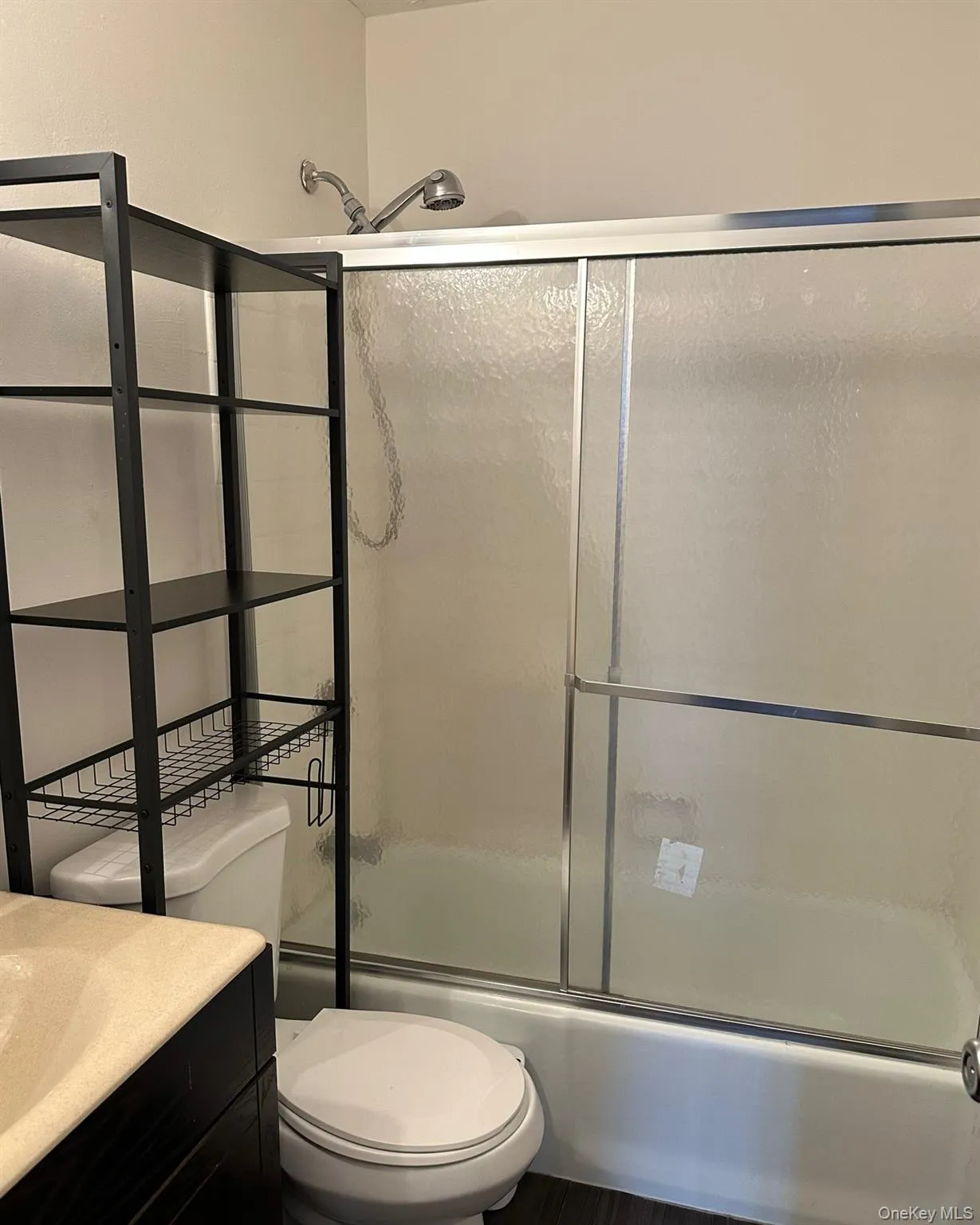 Full bath featuring bath / shower combo with glass door, vanity, and toilet Full bath featuring bath / shower combo with glass door, vanity, and toilet