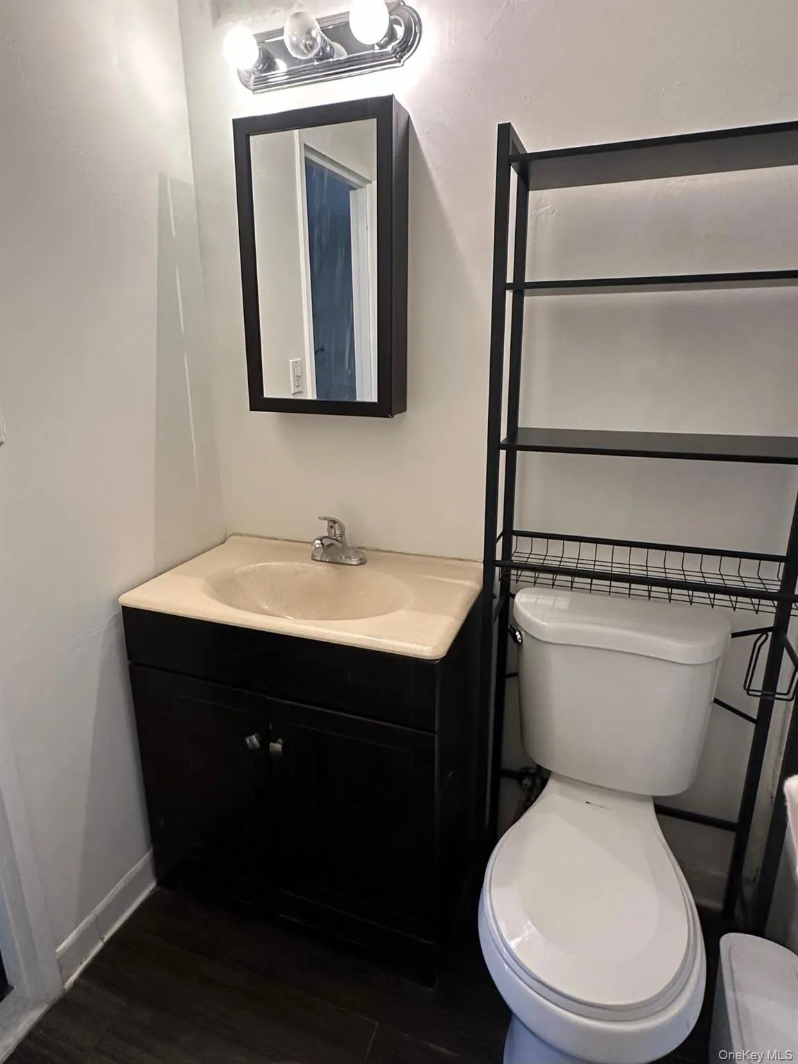 Half bath with vanity, baseboards, toilet, and wood finished floors Half bath with vanity, baseboards, toilet, and wood finished floors