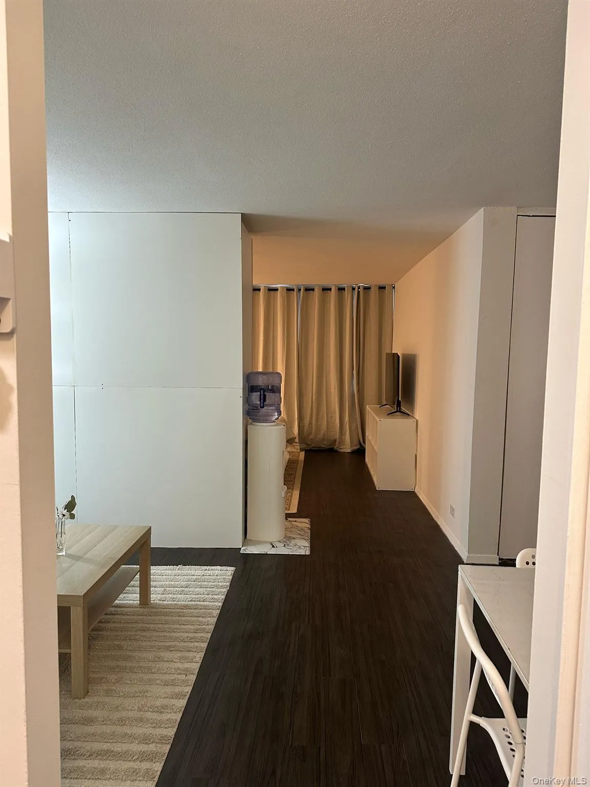 Hall featuring wood finished floors and a textured ceiling Hall featuring wood finished floors and a textured ceiling