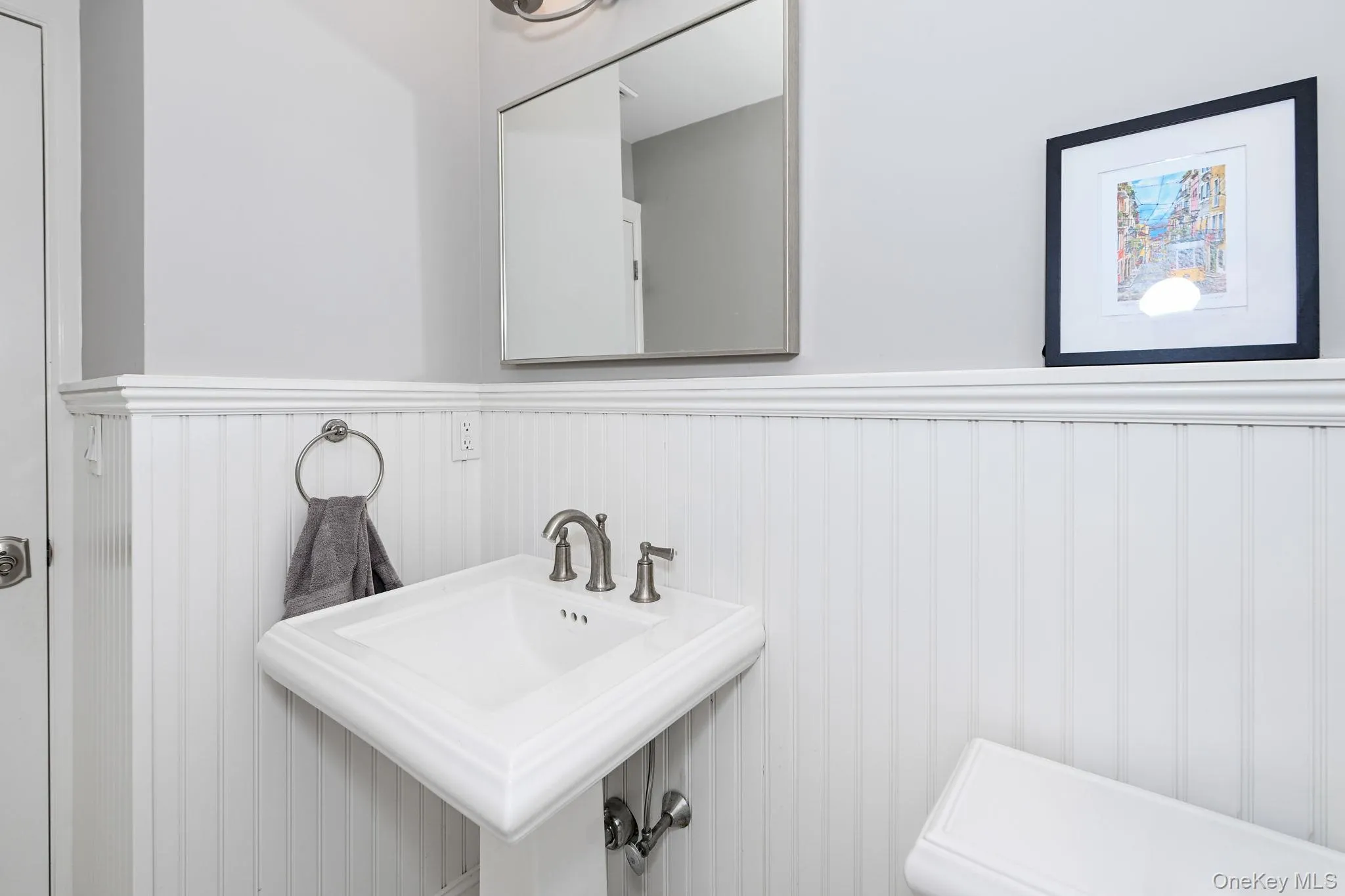 Adorned with classic wainscoting, this stylish powder room is perfectly situated just off the kitchen, offering both privacy and convenience. Adorned with classic wainscoting, this stylish powder room is perfectly situated just off the kitchen, offering both privacy and convenience.