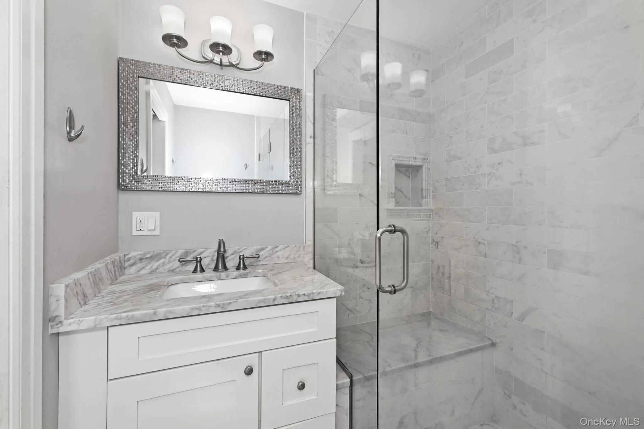 The owner’s bathroom features a glass-enclosed shower with a built-in bench, a large vanity sink, and elegant lighting paired with a decorative mirror. The owner’s bathroom features a glass-enclosed shower with a built-in bench, a large vanity sink, and elegant lighting paired with a decorative mirror.