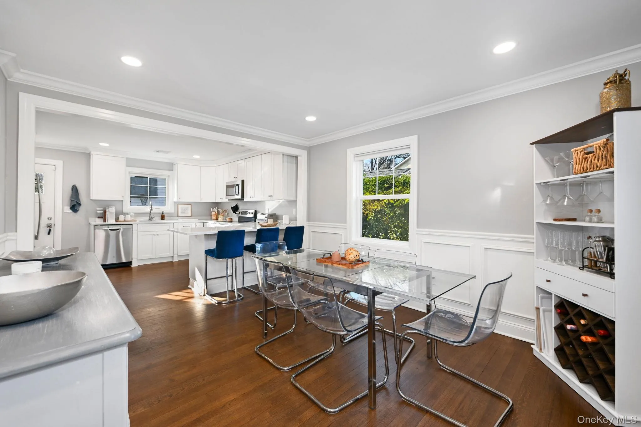 The formal dining room flows seamlessly into the gourmet kitchen, enhanced by recessed lighting, elegant wainscoting, and gleaming hardwood flooring. The formal dining room flows seamlessly into the gourmet kitchen, enhanced by recessed lighting, elegant wainscoting, and gleaming hardwood flooring.
