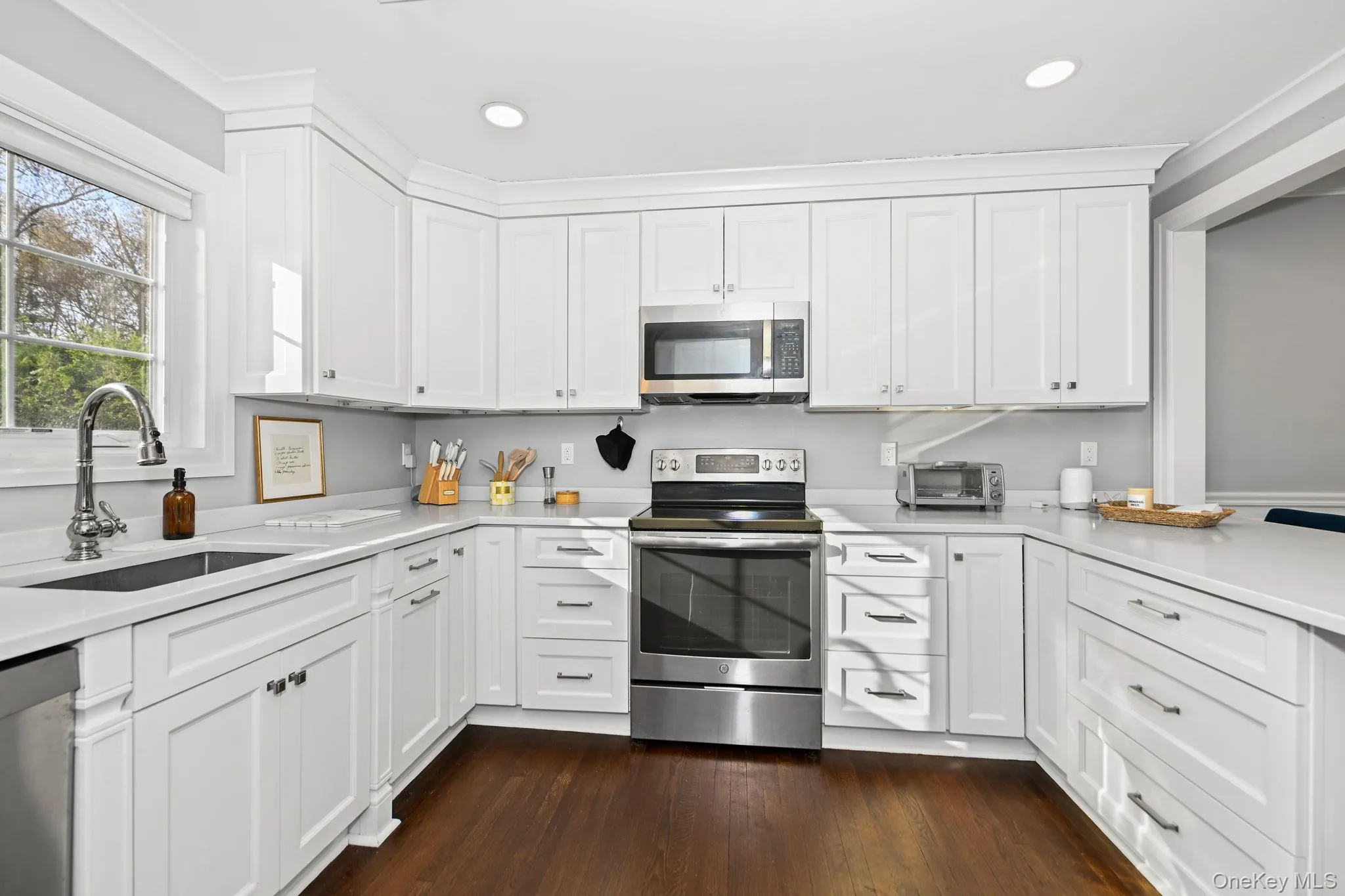 The heart of the home, this gourmet kitchen features custom wood cabinetry, stone countertops, recessed lighting, and a convenient storage closet. An oversized stainless steel sink sits beneath a sunlit window, complemented by top-of-the-line stainless steel GE appliances. The heart of the home, this gourmet kitchen features custom wood cabinetry, stone countertops, recessed lighting, and a convenient storage closet. An oversized stainless steel sink sits beneath a sunlit window, complemented by top-of-the-line stainless steel GE appliances.