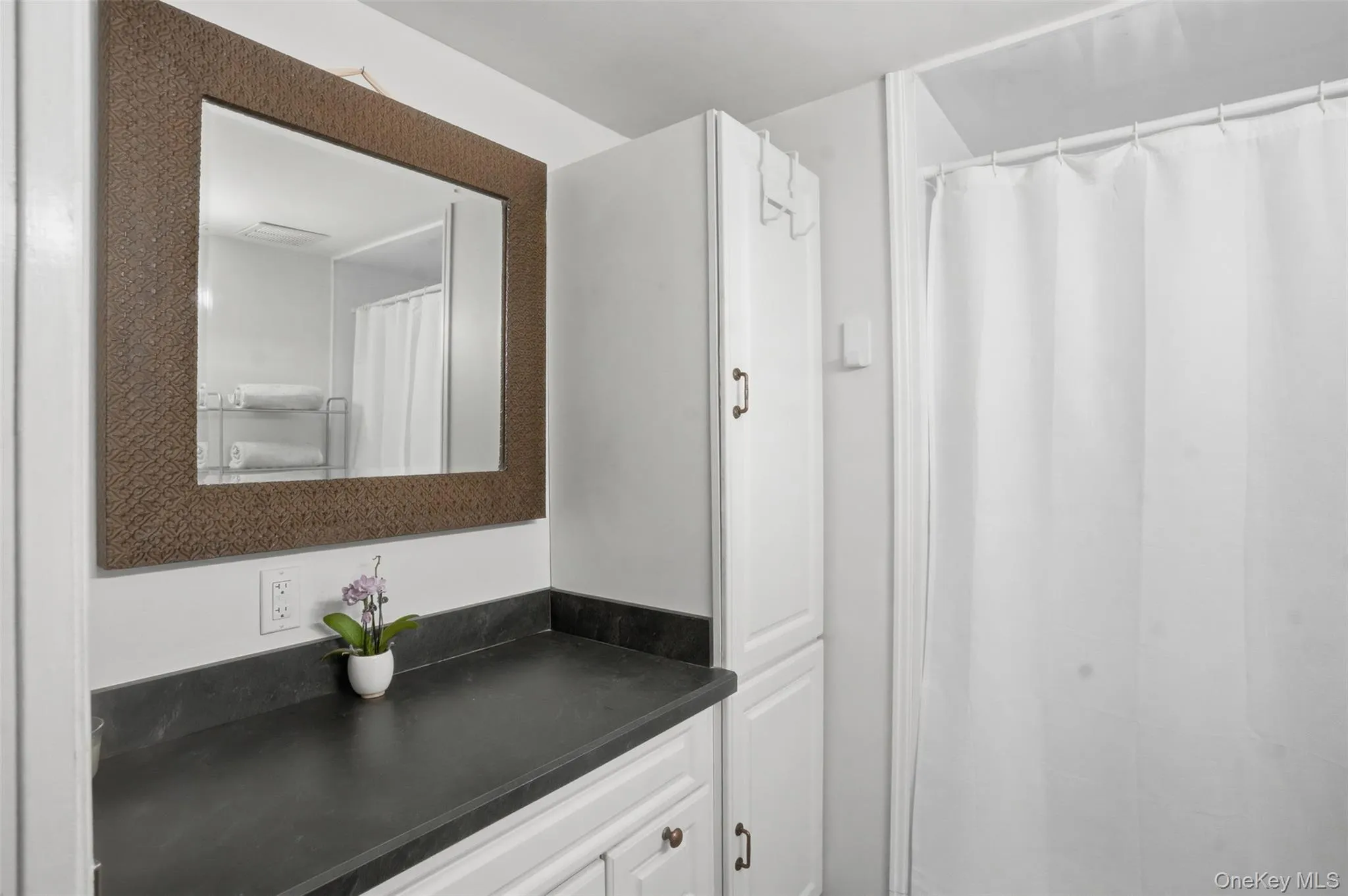 Bathroom vanity with a dark countertop and a framed mirror Bathroom vanity with a dark countertop and a framed mirror