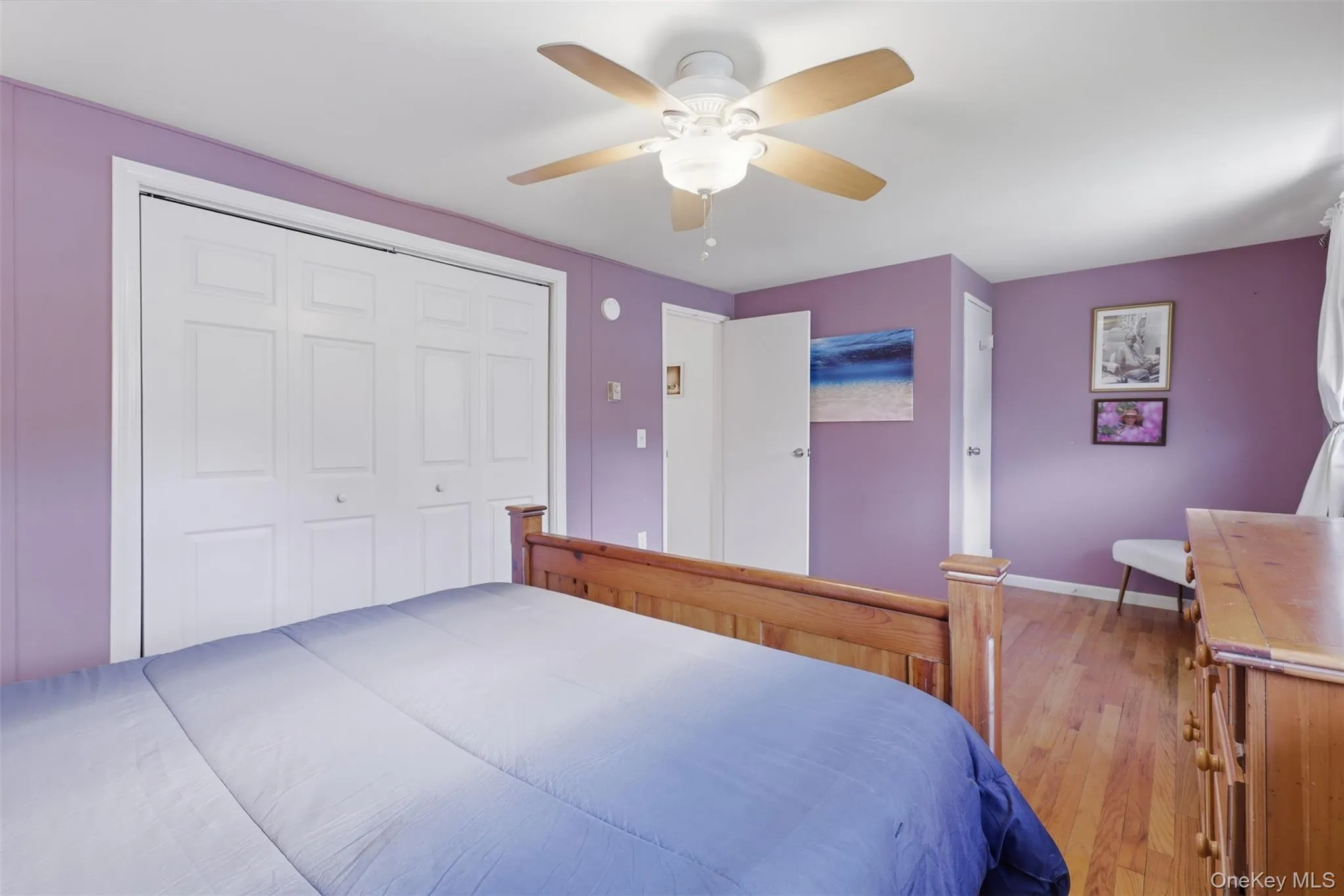 Interior room featuring wood-finish flooring, a ceiling fan, and white bi-fold closet doors Interior room featuring wood-finish flooring, a ceiling fan, and white bi-fold closet doors
