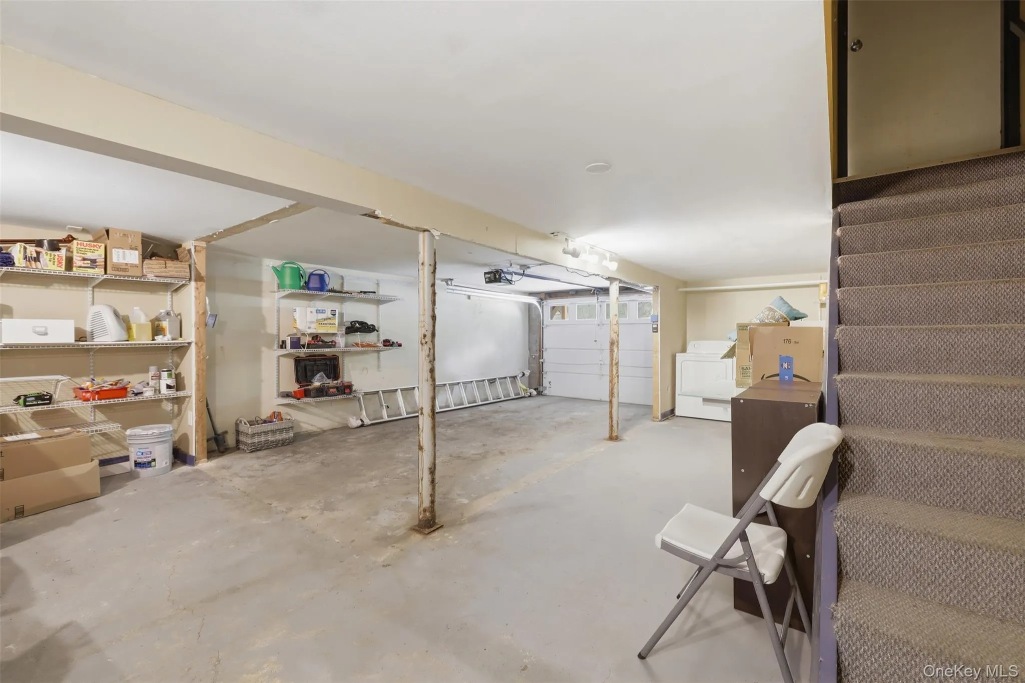 Finished basement area featuring concrete flooring and exposed structural beams Finished basement area featuring concrete flooring and exposed structural beams