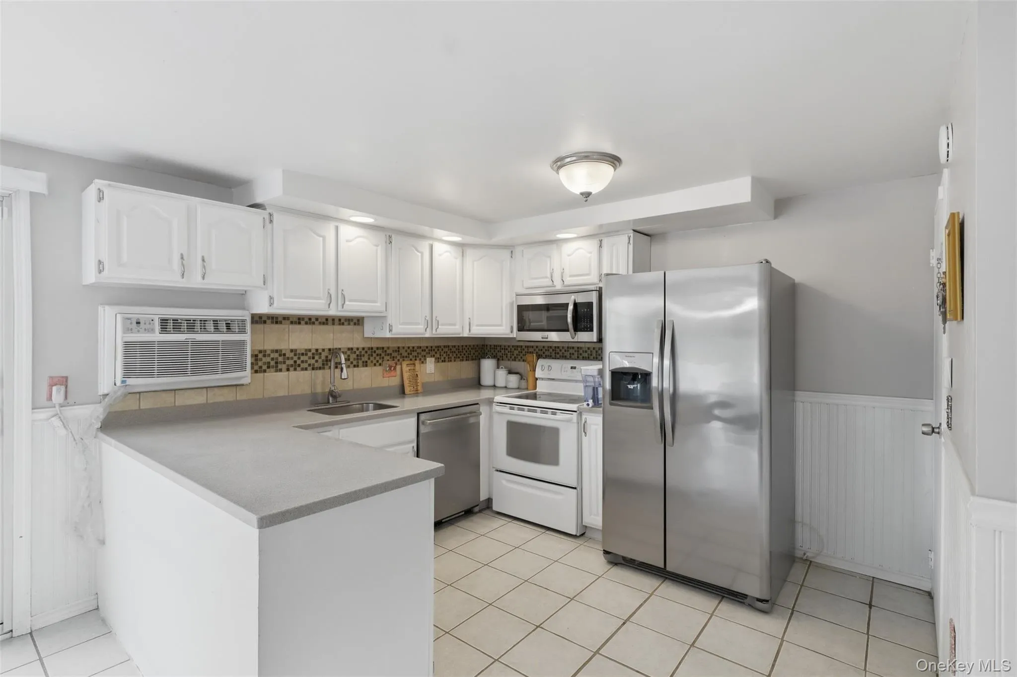 Kitchen featuring white cabinetry, a neutral tiled backsplash, stainless steel appliances, Kitchen featuring white cabinetry, a neutral tiled backsplash, stainless steel appliances,