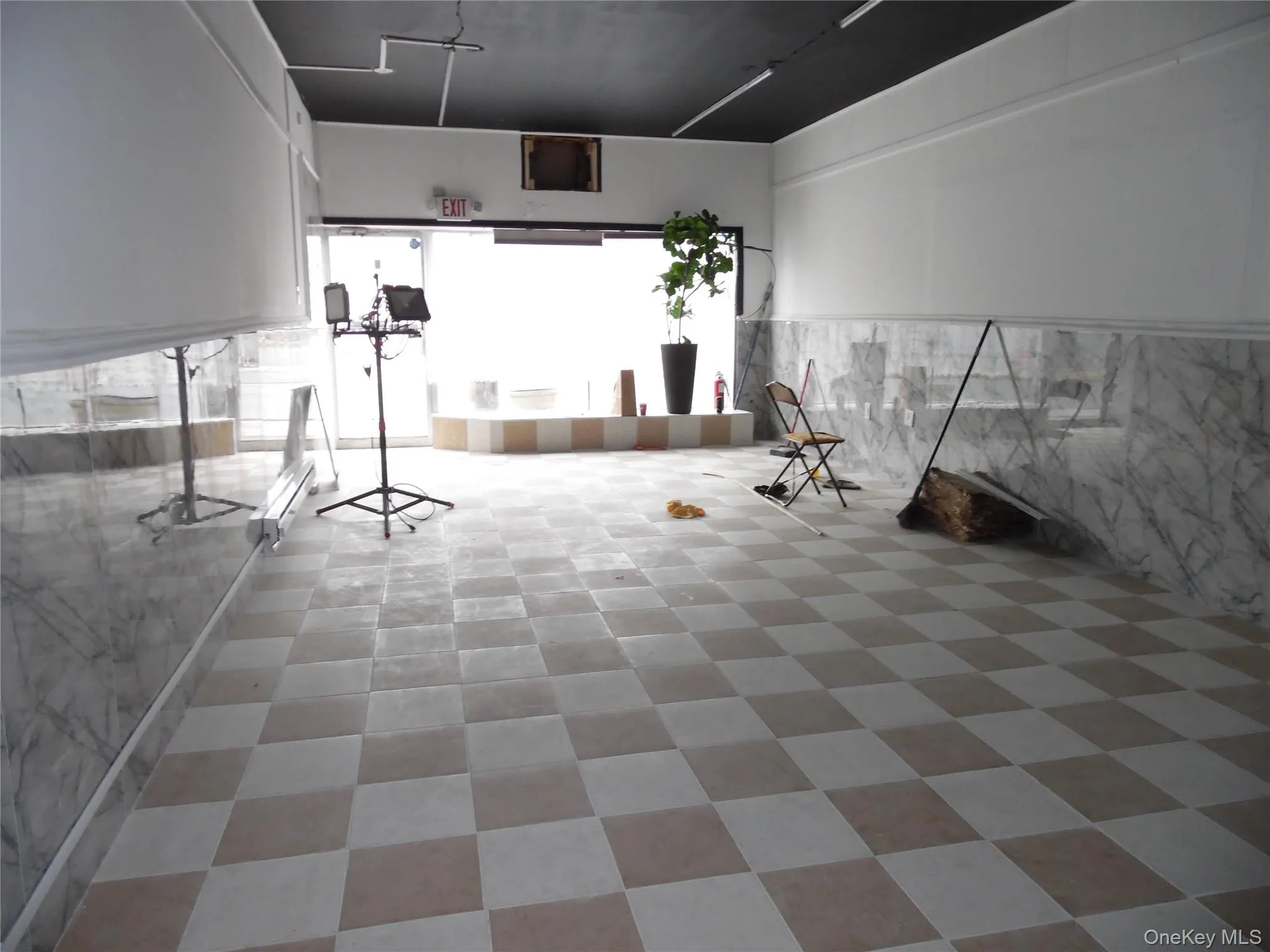 The interior features a checkered tile floor, marble-patterned wainscoting, and a dark-colored ceiling The interior features a checkered tile floor, marble-patterned wainscoting, and a dark-colored ceiling