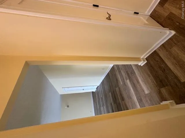 Hallway with dark wood-type flooring and baseboards Hallway with dark wood-type flooring and baseboards