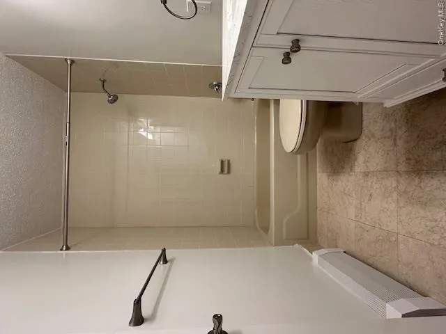 Bathroom with shower combination, toilet, vanity, and a textured ceiling Bathroom with shower combination, toilet, vanity, and a textured ceiling