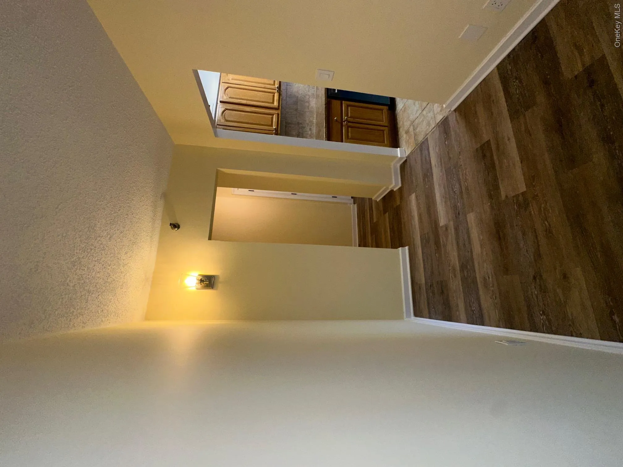 Hallway featuring baseboards, wood finished floors, and a textured ceiling Hallway featuring baseboards, wood finished floors, and a textured ceiling