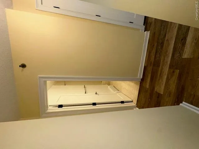 Hall with baseboards, wood finished floors, and a textured ceiling Hall with baseboards, wood finished floors, and a textured ceiling