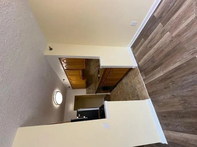 Kitchen with baseboards, a textured ceiling, dishwasher, a sink, and wood finished floors Kitchen with baseboards, a textured ceiling, dishwasher, a sink, and wood finished floors