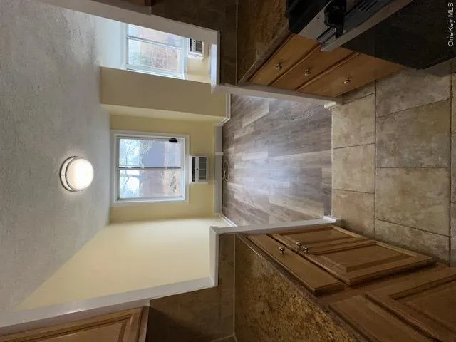 Unfurnished dining area featuring light wood finished floors, baseboards, a textured ceiling, and a wall unit AC Unfurnished dining area featuring light wood finished floors, baseboards, a textured ceiling, and a wall unit AC