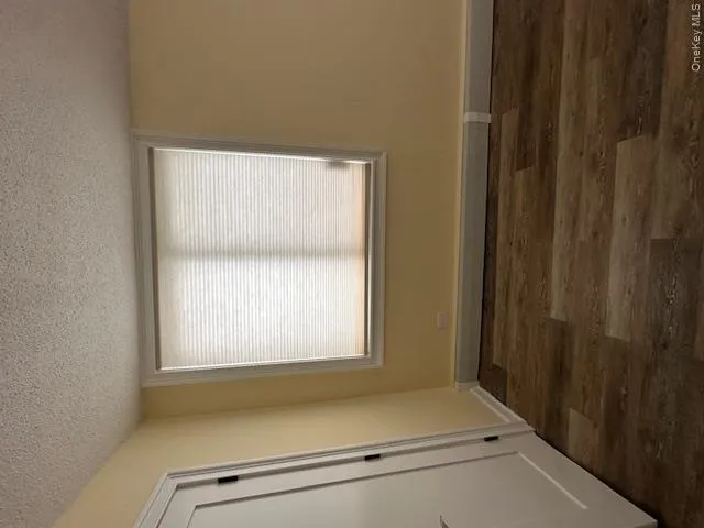 Unfurnished room with a healthy amount of sunlight, dark wood-style floors, and a textured ceiling Unfurnished room with a healthy amount of sunlight, dark wood-style floors, and a textured ceiling