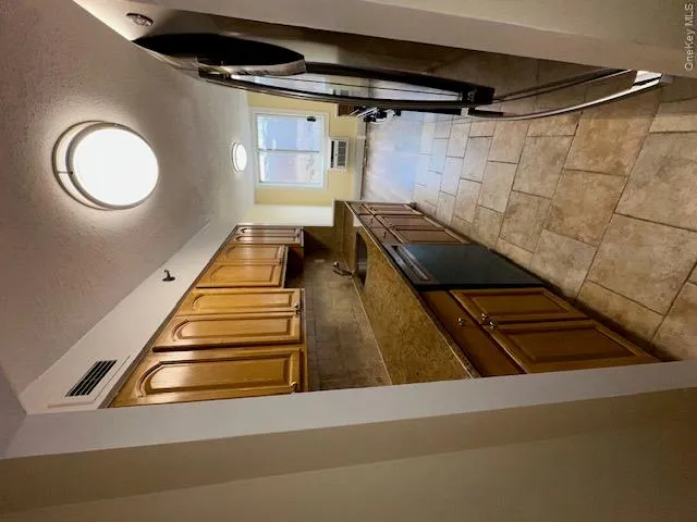 Kitchen featuring visible vents, a wall unit AC, dishwashing machine, fridge, and a sink Kitchen featuring visible vents, a wall unit AC, dishwashing machine, fridge, and a sink
