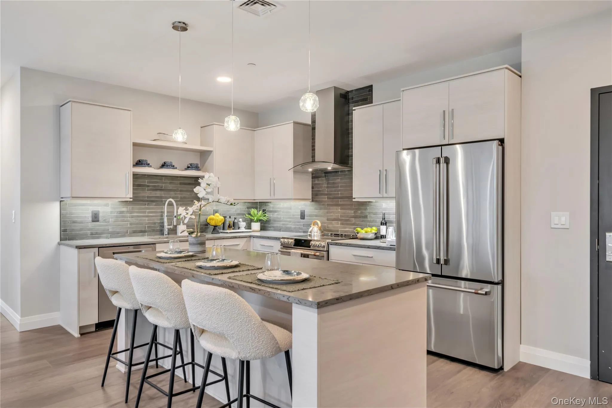 Kitchen featuring a breakfast bar, baseboards, wall chimney exhaust hood, a sink, and appliances with stainless steel finishes Kitchen featuring a breakfast bar, baseboards, wall chimney exhaust hood, a sink, and appliances with stainless steel finishes