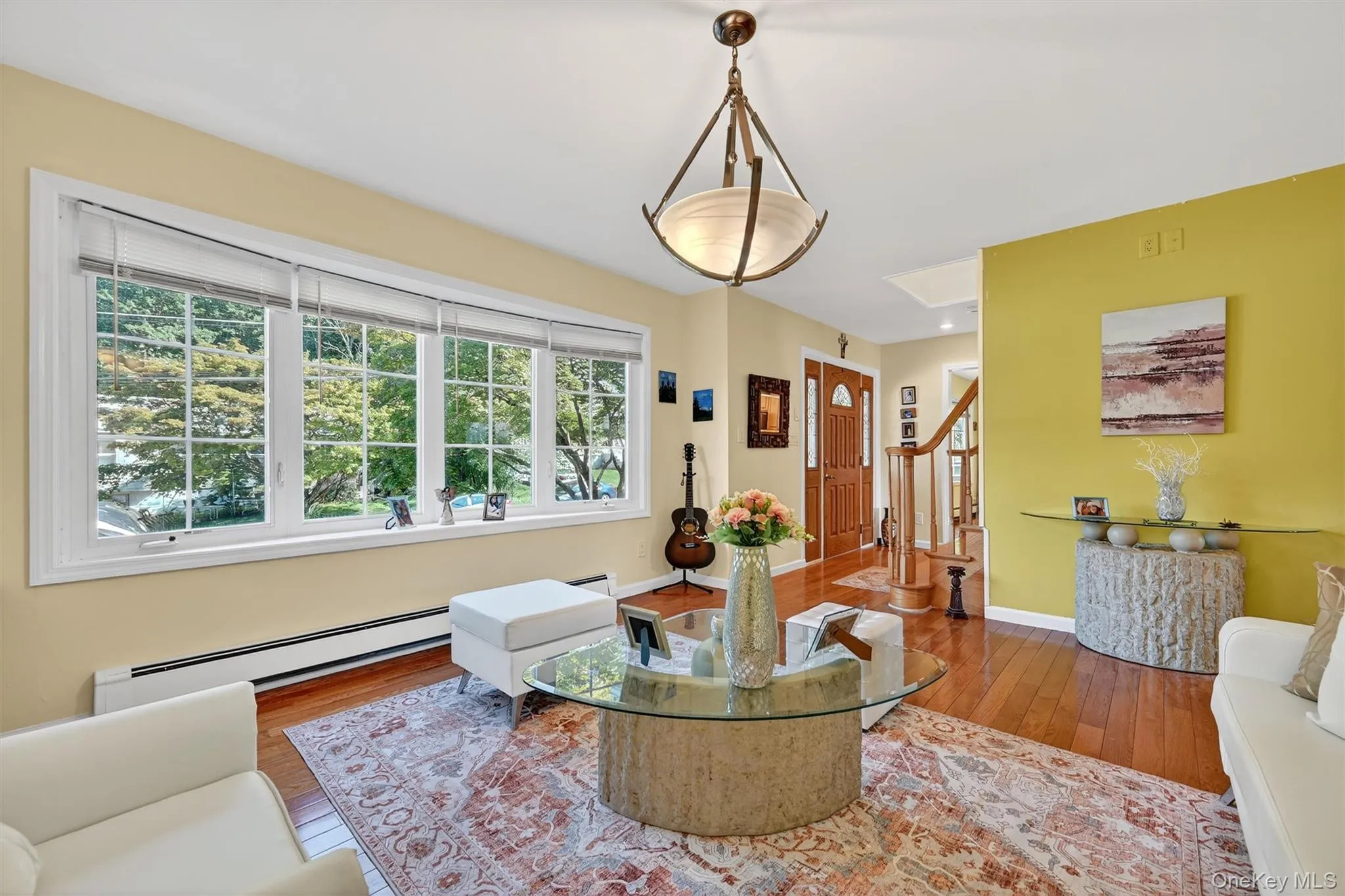 Living area with baseboard heating, hardwood / wood-style floors, and stairs Living area with baseboard heating, hardwood / wood-style floors, and stairs