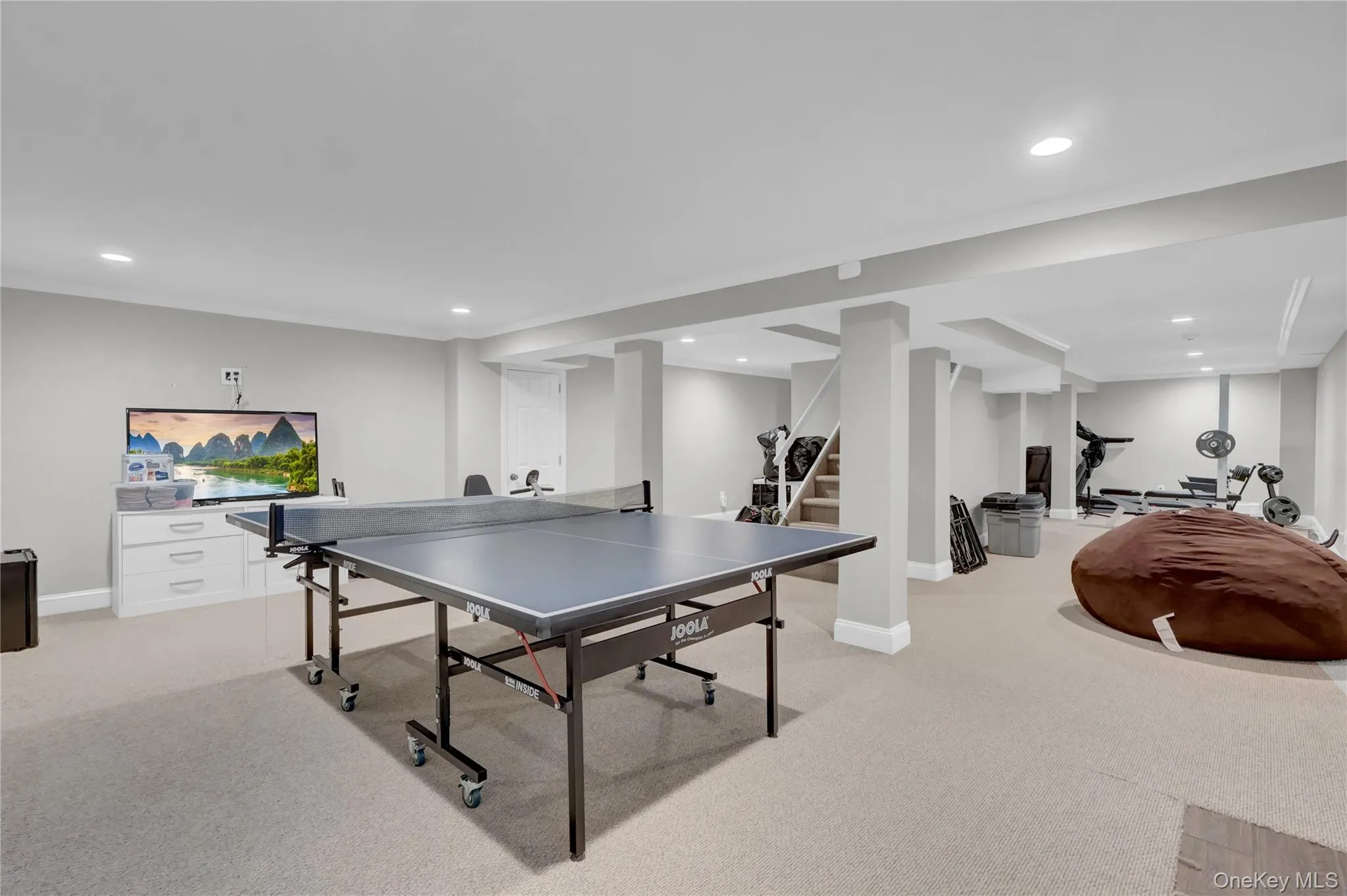 Spacious finished basement featuring recessed lighting, light-colored carpeting, multiple support columns, and crown molding Spacious finished basement featuring recessed lighting, light-colored carpeting, multiple support columns, and crown molding
