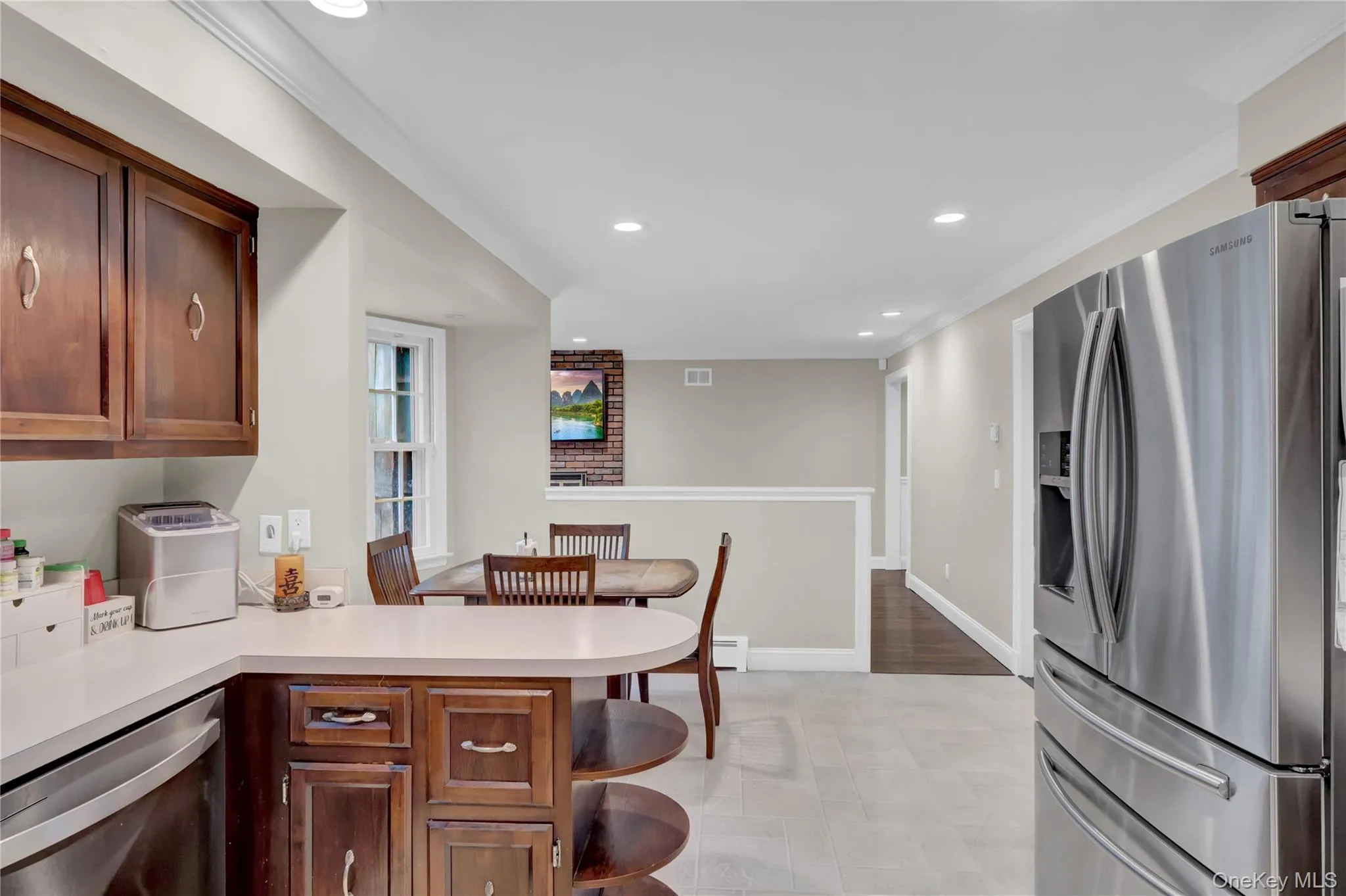 Kitchen featuring wood cabinetry, light-toned countertops, and stainless steel appliances Kitchen featuring wood cabinetry, light-toned countertops, and stainless steel appliances
