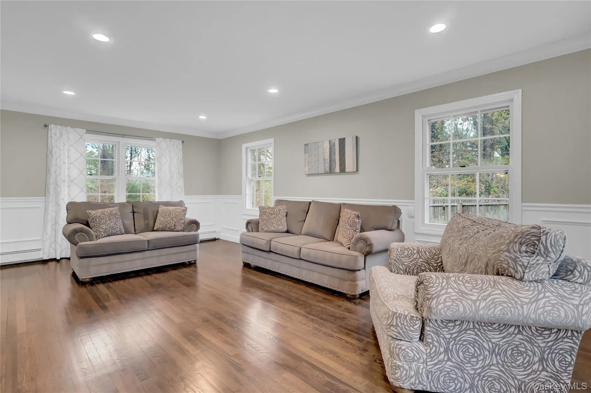 Spacious living area featuring wood-finish flooring, recessed lighting, and crown molding Spacious living area featuring wood-finish flooring, recessed lighting, and crown molding