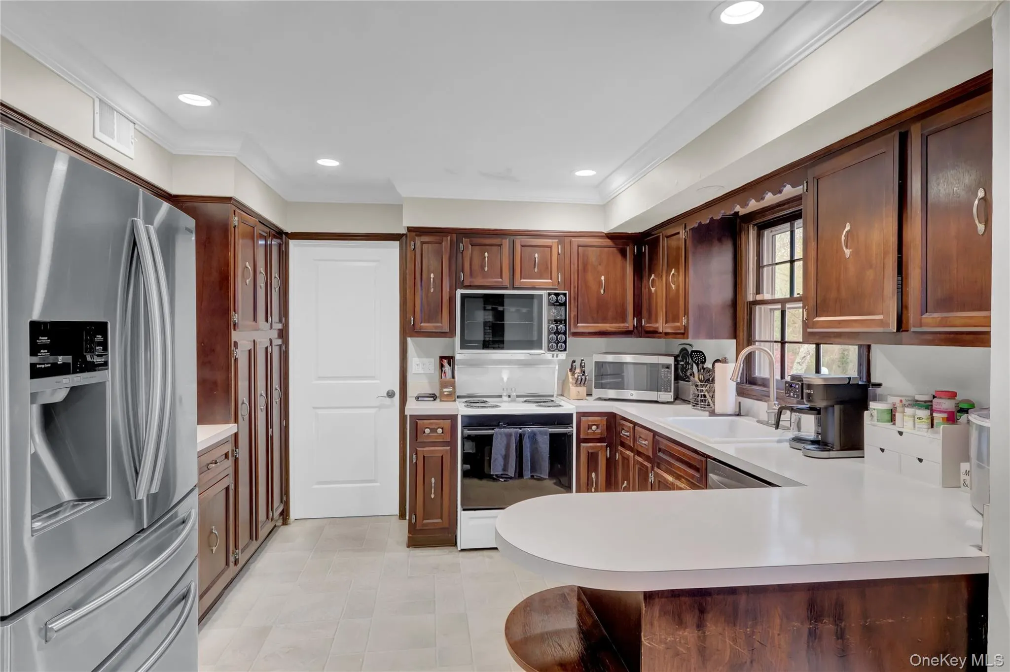 Kitchen featuring extensive wood cabinetry, light countertops, and tile flooring Kitchen featuring extensive wood cabinetry, light countertops, and tile flooring