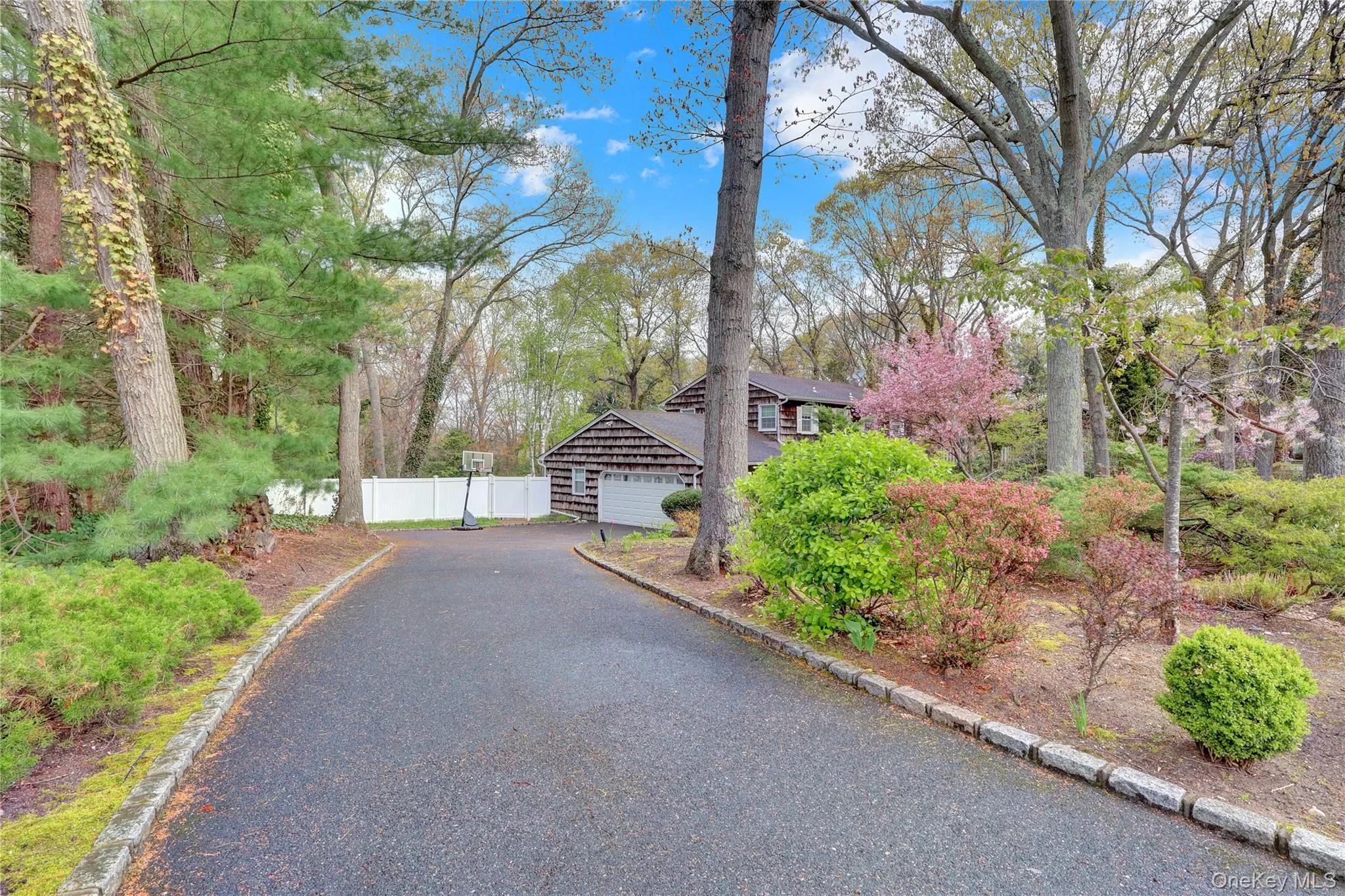 Paved driveway bordered by stone curbing, leading to a residence with a two-car garage Paved driveway bordered by stone curbing, leading to a residence with a two-car garage