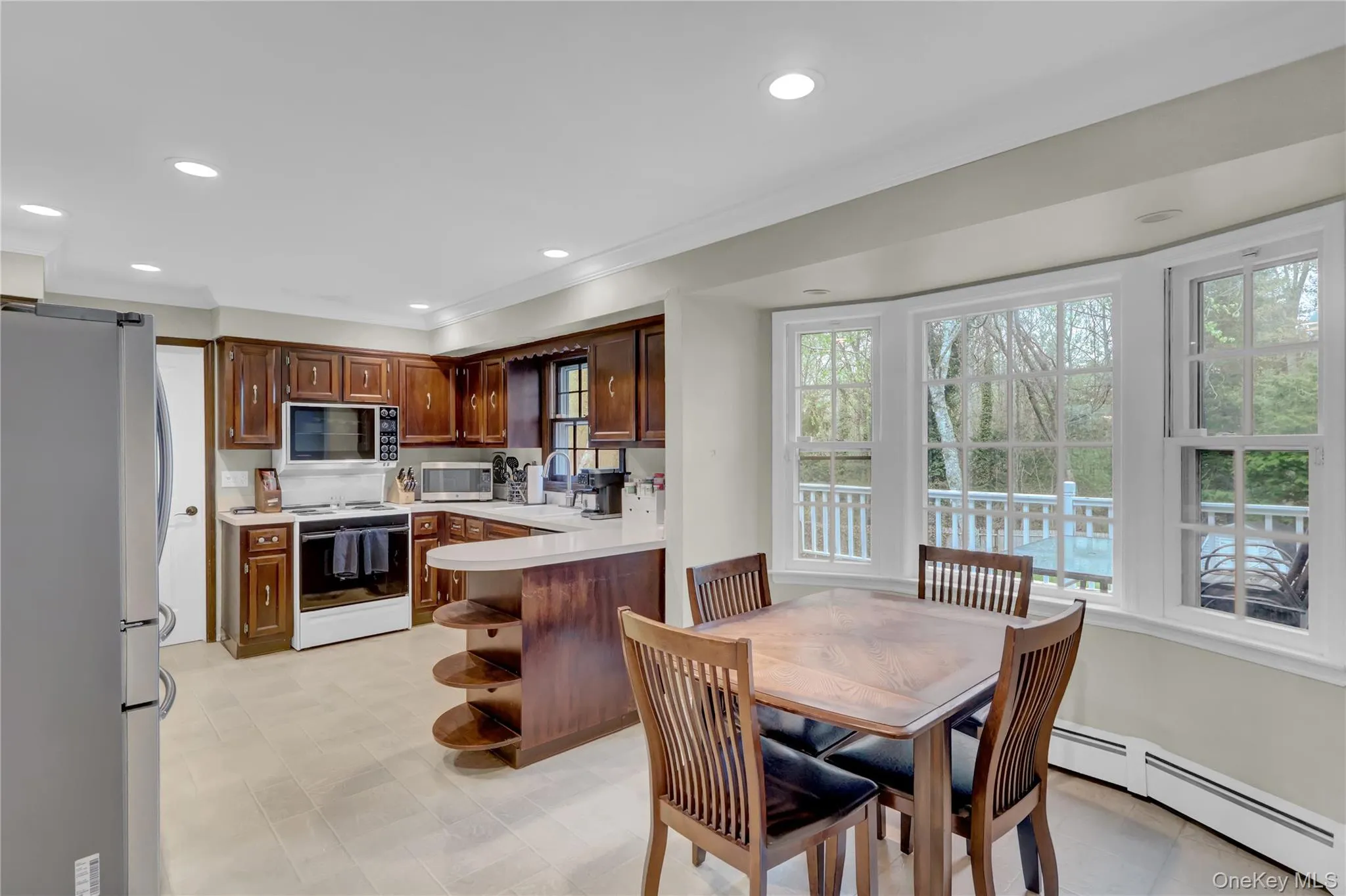 Eat-in kitchen featuring wood cabinetry, recessed lighting, and a bay window overlooking a deck Eat-in kitchen featuring wood cabinetry, recessed lighting, and a bay window overlooking a deck